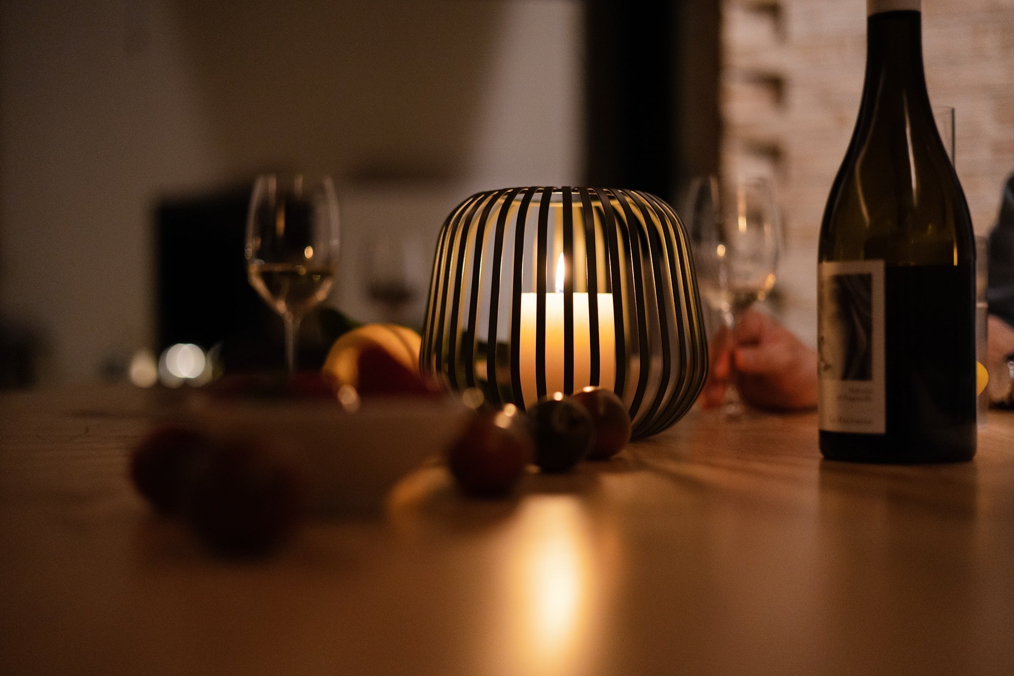 Die Solarlaterne Solis wird als stilvolles Windlicht mit Kerze bei einem gemütlichen Abendessen mit Wein und Obst genutzt – warme, romantische Lichtstimmung für Innen- und Außenbereiche.