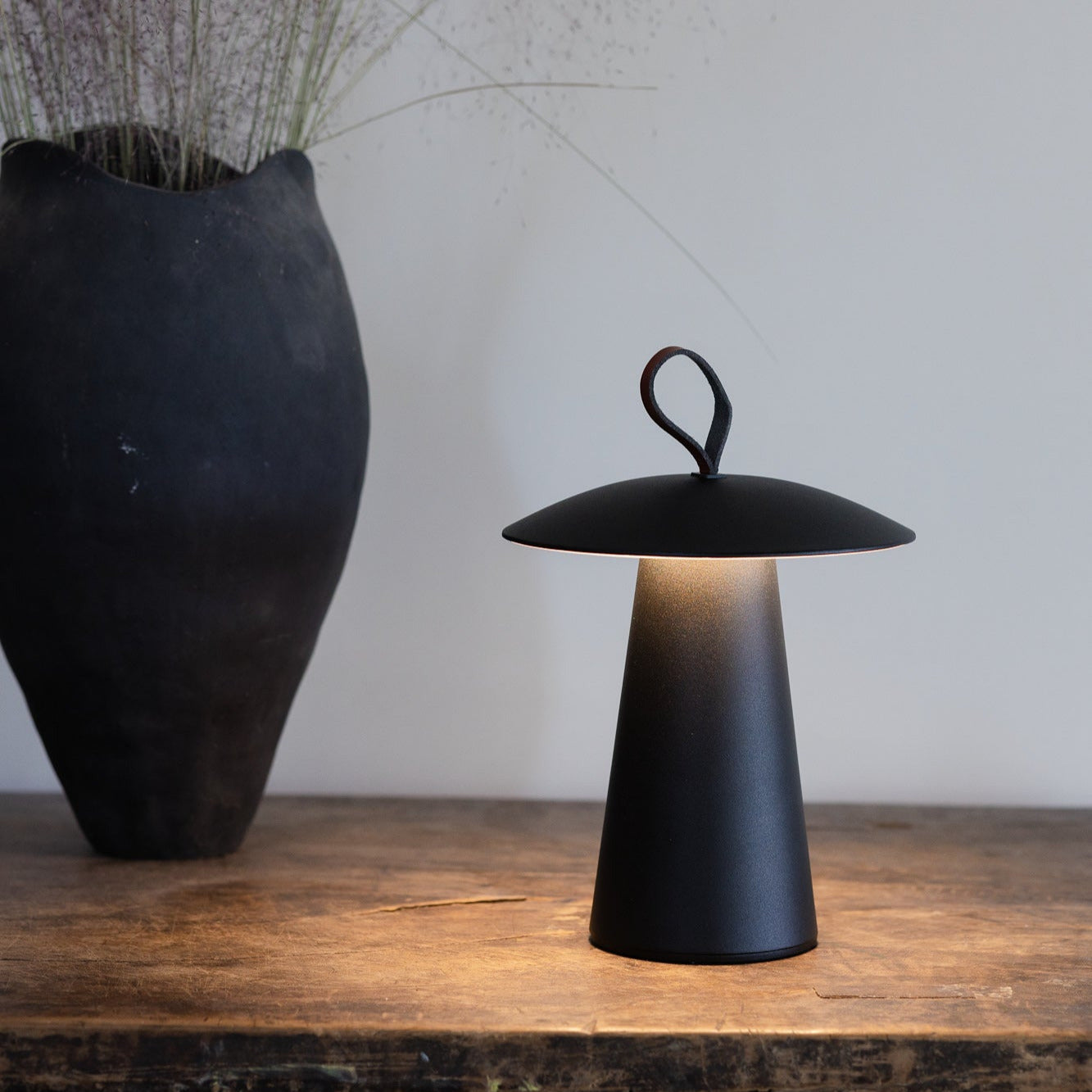 Minimalistische und dimmbare Lyvo Tischlampe schwarz auf Holztisch mit warmweißen Licht