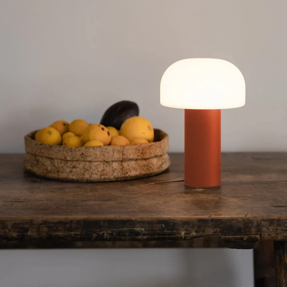Die leuchtende LED NOA Laterne von LUUK Studio in der Limited Edition Farbe Persimone auf elegantem Esstisch mit Obstschale.