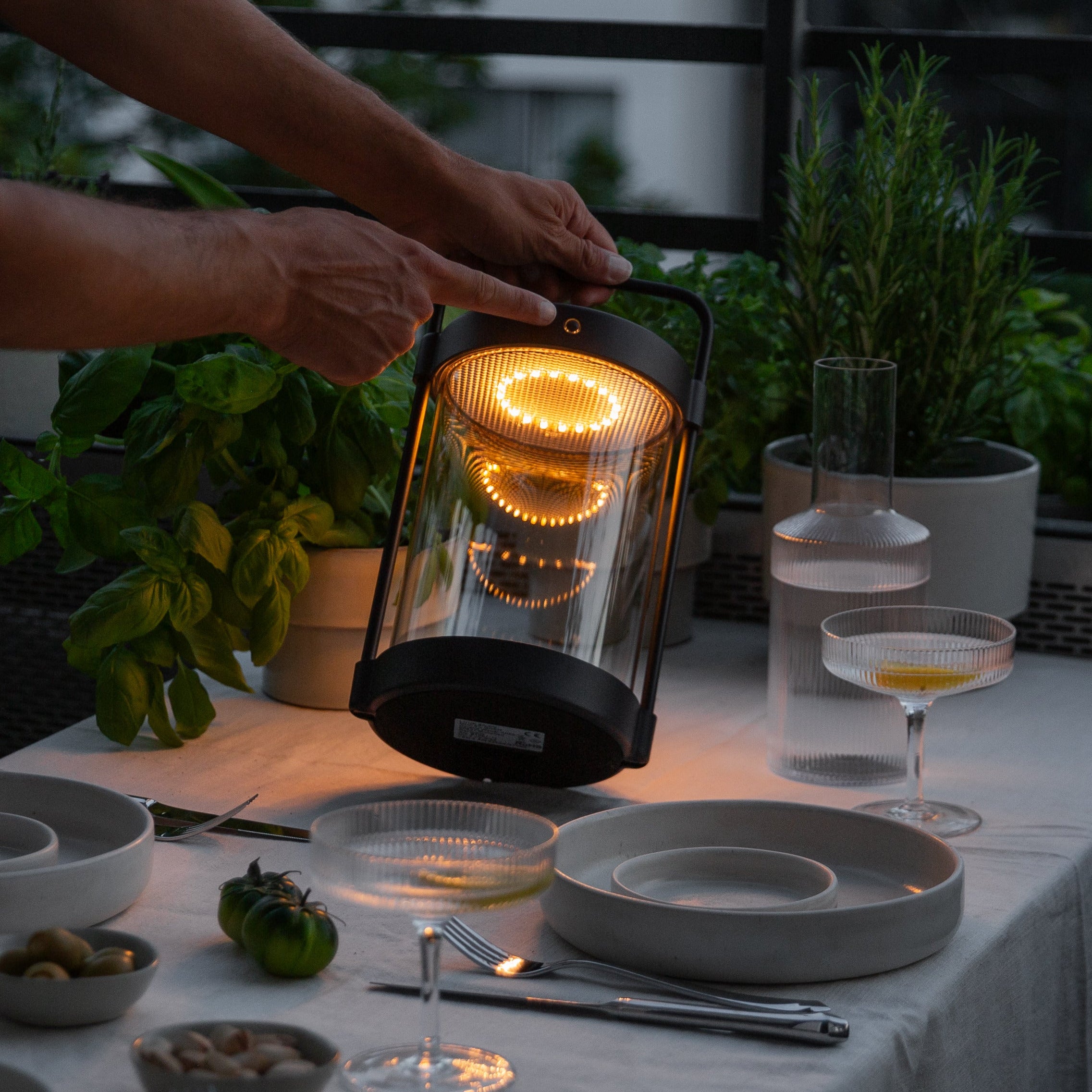 Caia LED-Solarlaterne in Schwarz mit Echtglas – stimmungsvolle Beleuchtung auf gedecktem Terrassentisch bei Abenddämmerung