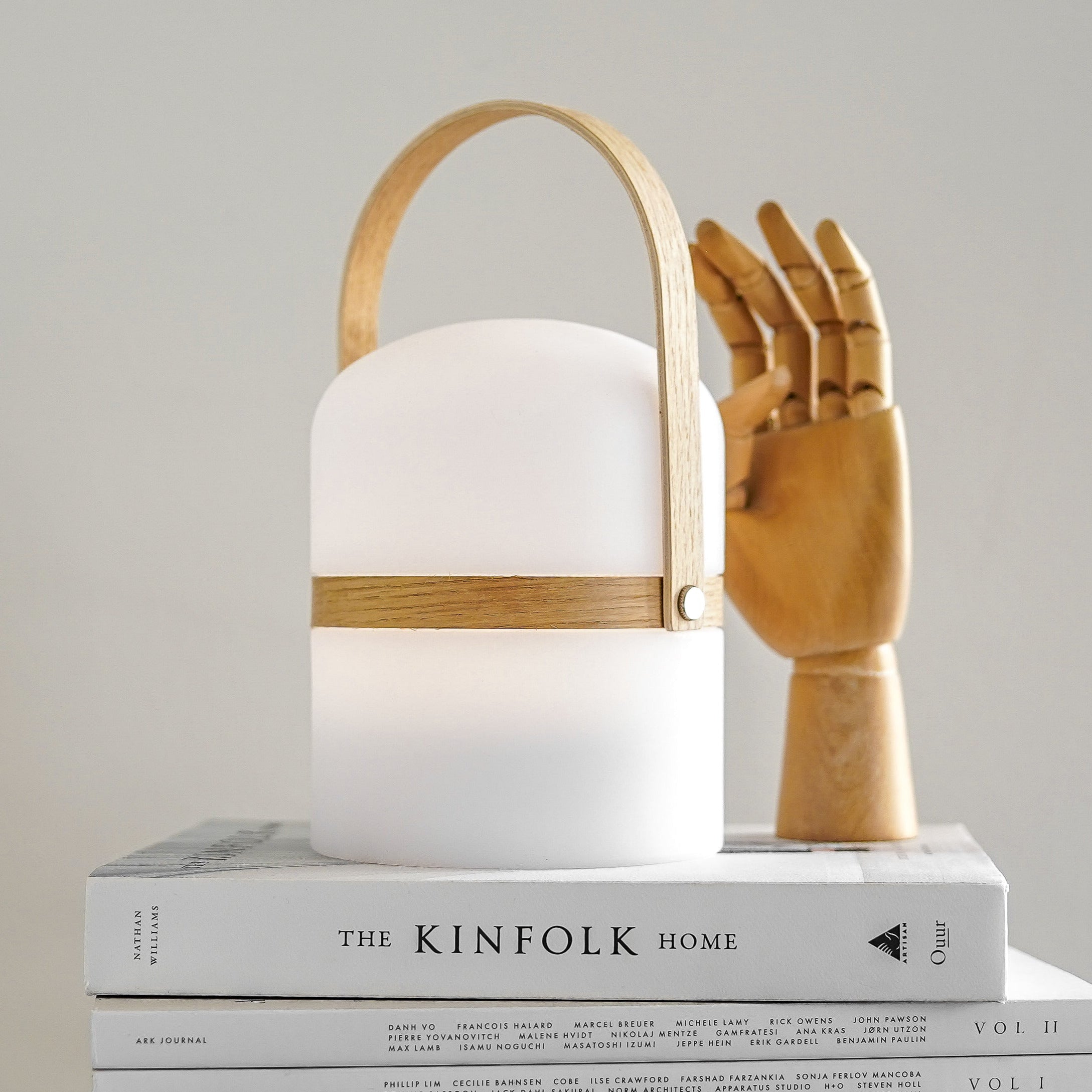 Tragbare LED-Tischleuchte Luma mit Holzgriff – modernes Wohnaccessoire mit warmweißem Licht auf Designbüchern arrangiert