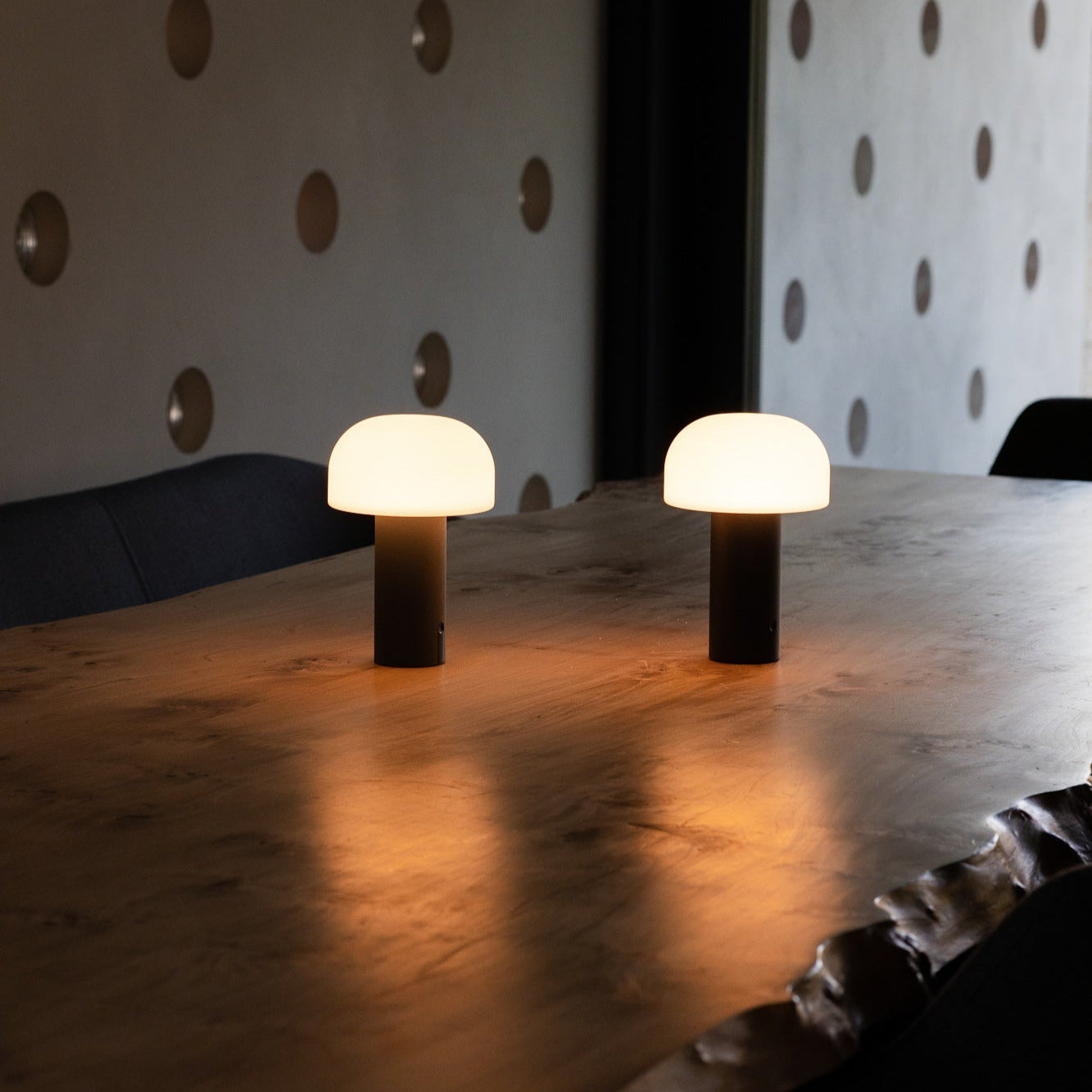 Zwei Noa LED-Tischleuchten in Grau und Schwarz auf Esstisch – moderne, dimmbare Akkuleuchte mit warmweißem Licht für vielseitige Einsatzbereiche