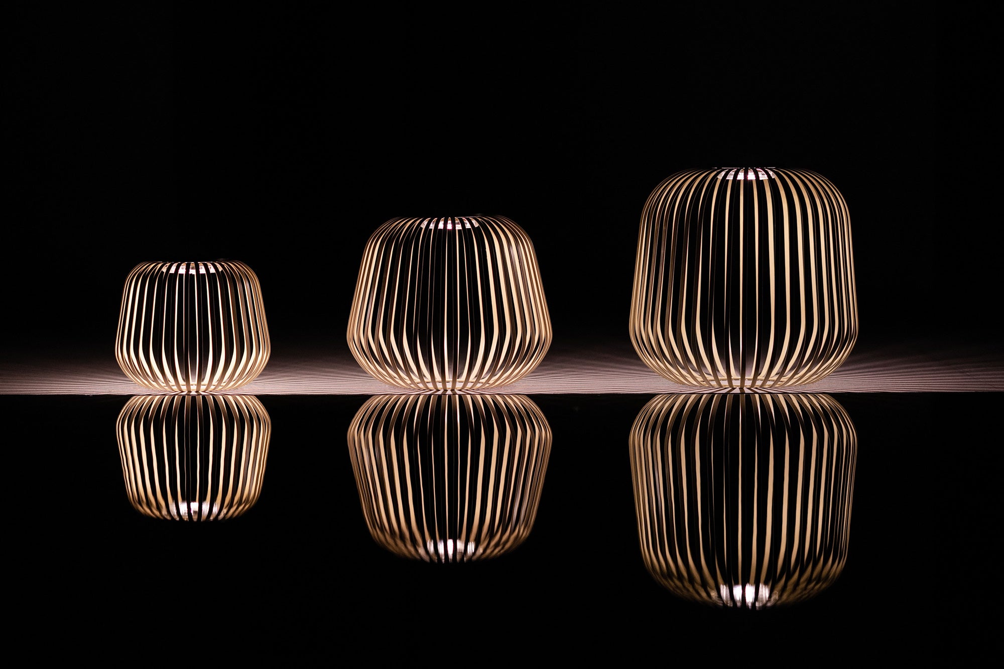 Drei beleuchtete Solis Solarlaternen mit herausnehmbaren Solarmodul in Gelb für draußen mit atmosphärischer Spiegelung bei Nacht