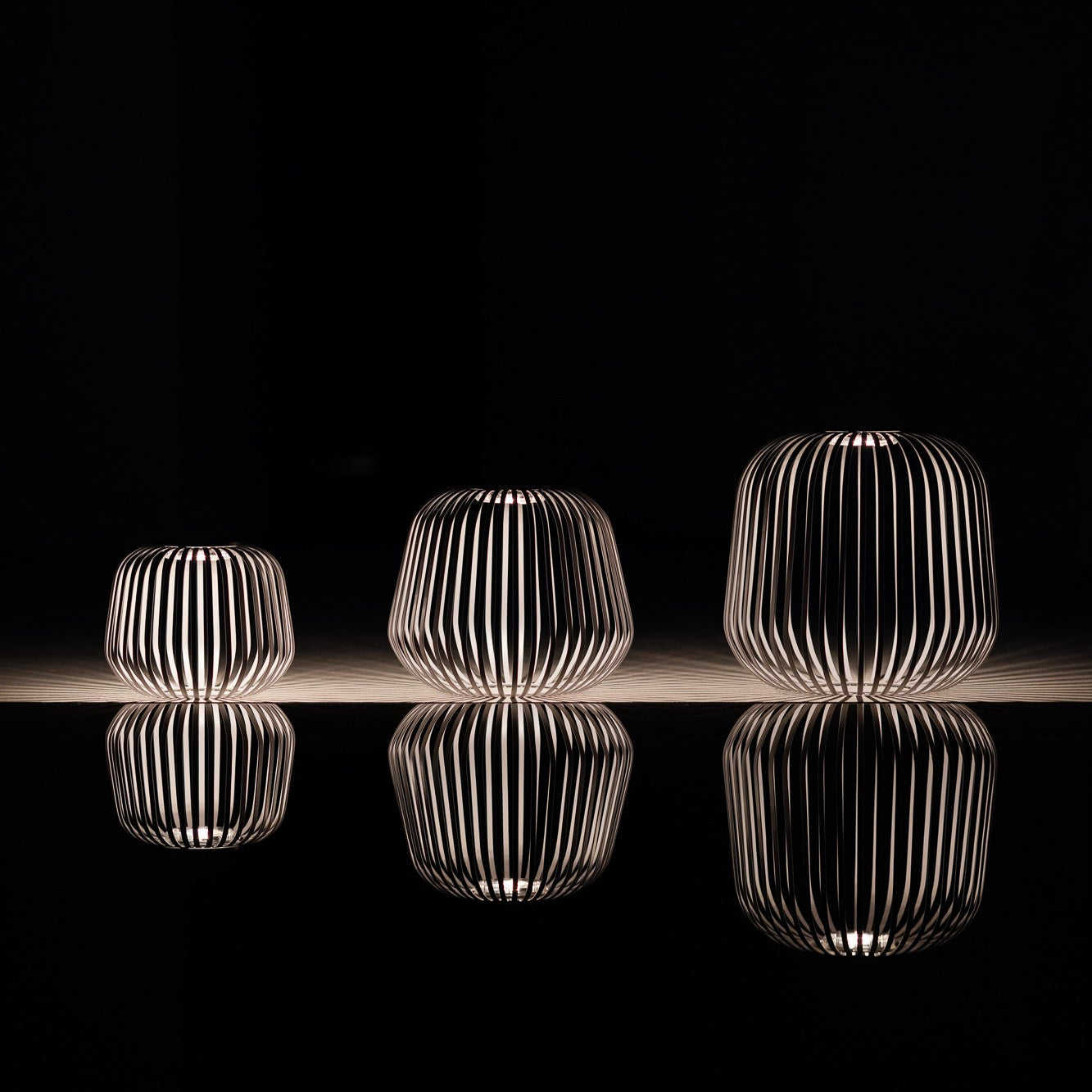 Drei LUUK Studio Solarlampen bei Nacht mit Spiegelung und Licht-Schatten-Spiel auf dunkler Oberfläche