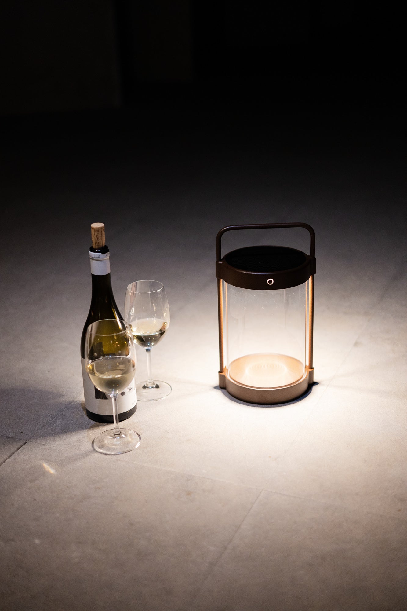 Stimmungsvolle Outdoor-Laterne mit warmweißem Licht auf der Terrasse mit Weinglas