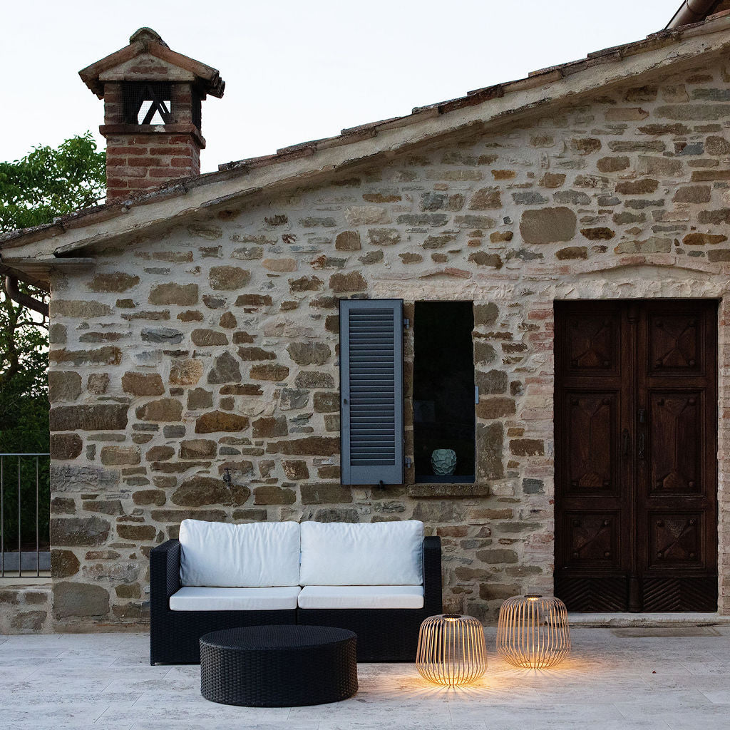 Die Solis Solarlampen in XL und XXL vor einem restaurierten Steinhaus in Italien neben einem Outdoor Sofa als Statement Piece.