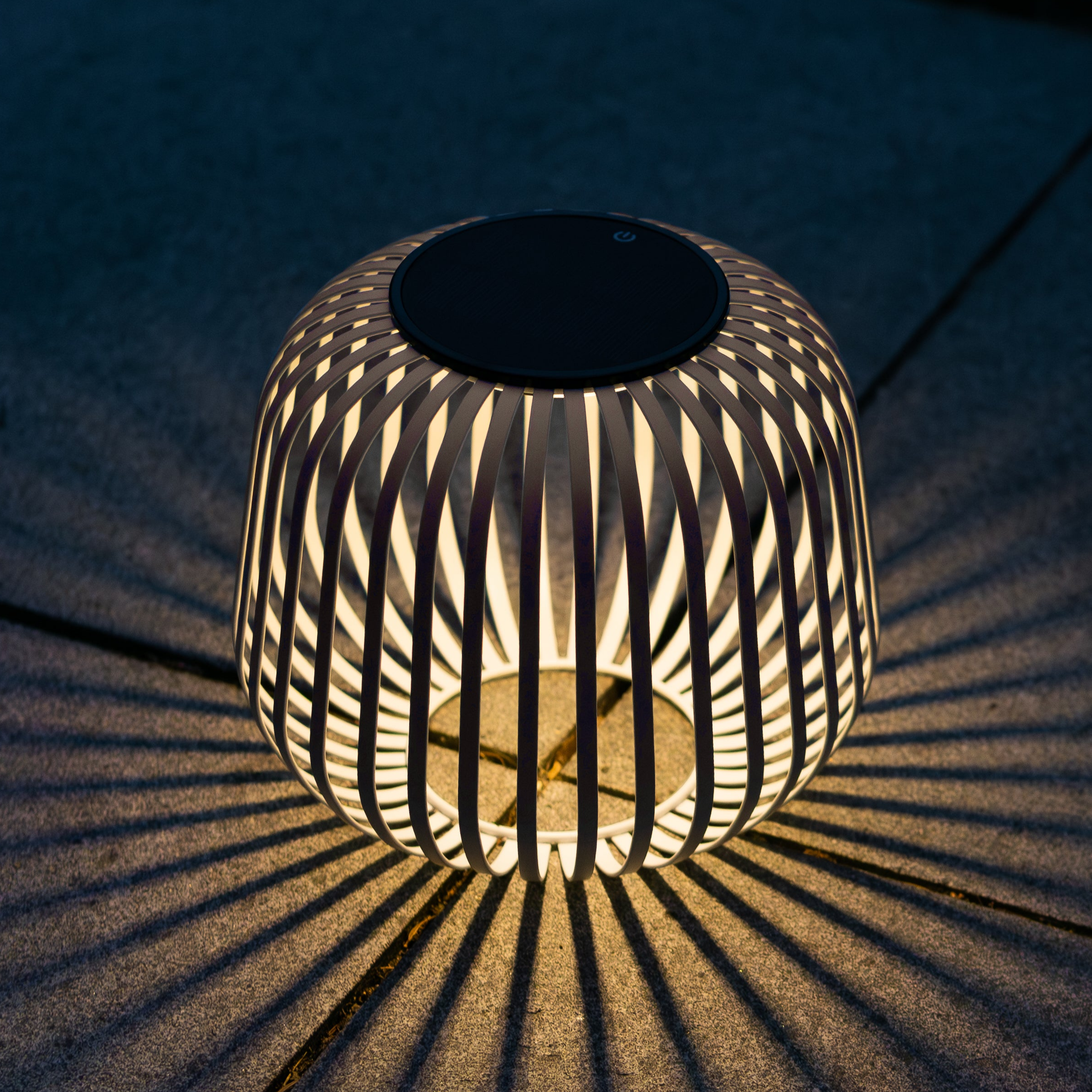 Solis Solarlaterne von LUUK Studio bei Nacht – atmosphärisches Lichtspiel mit dekorativen Schatteneffekten auf dem Boden