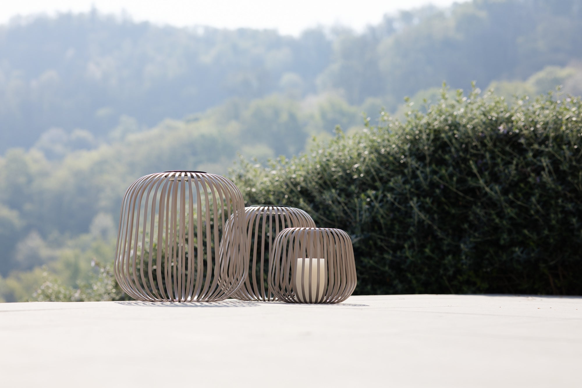 3er Solis Solarlaternen Set in Nomad Braun bei Tageslicht auf dem Boden einer auf Steinterrasse mit Kerze als Windlicht.