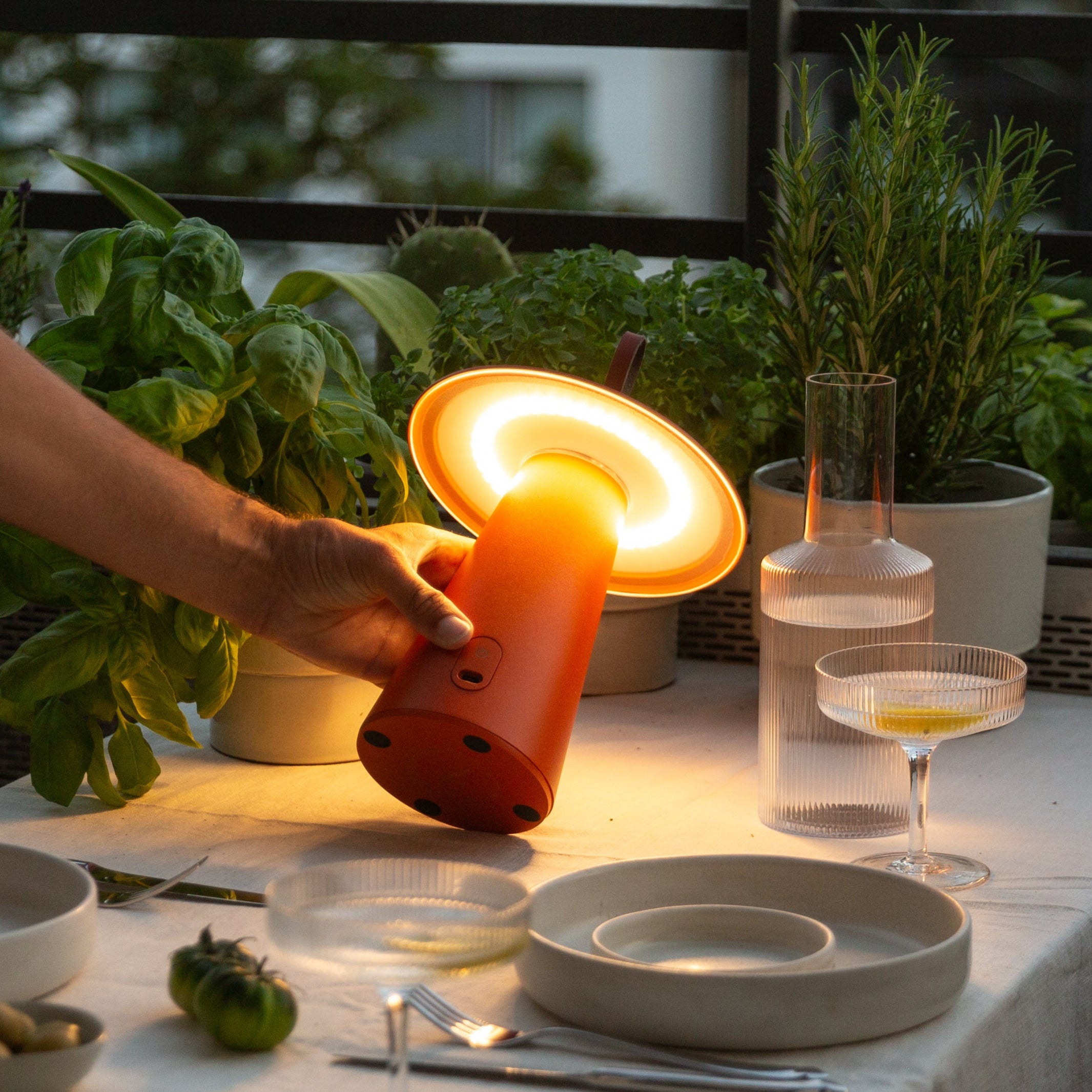 LED-Tischleuchte Lyvo in Orange im Einsatz beim Abendessen auf dem Balkon – tragbare, stimmungsvolle Beleuchtung mit dimmbarem Licht für Indoor und Outdoor