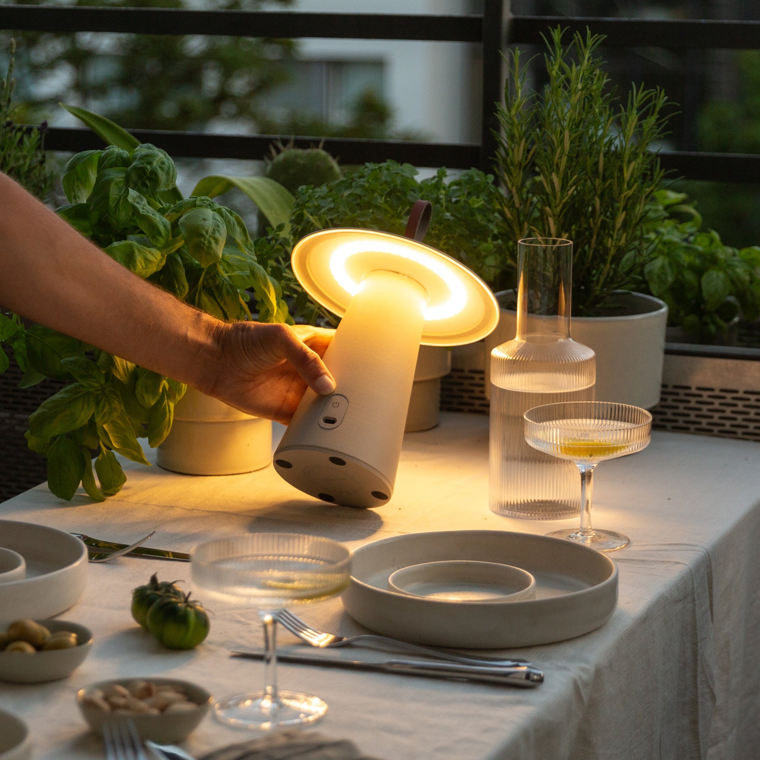 Weiße LED-Tischleuchte Lyvo spendet stimmungsvolles Licht beim stilvollen Abendessen auf dem Balkon – ideal für Designverliebe Gastgeber