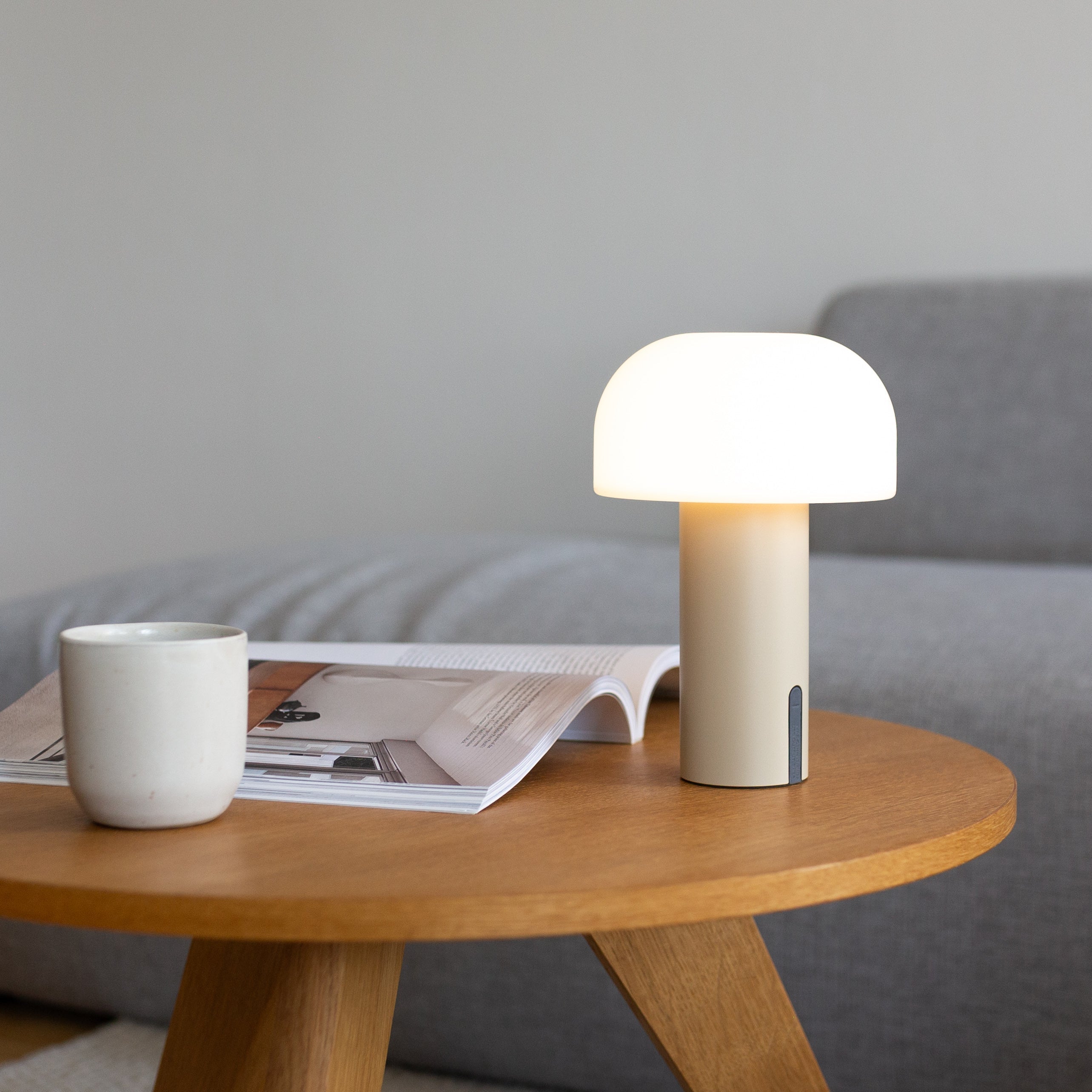 Stufenlos dimmbare und minimalistische LED-Tischleuchte in Cremeweiß von LUUK Studio auf Couchtisch – kabellos, stilvoll und mobil