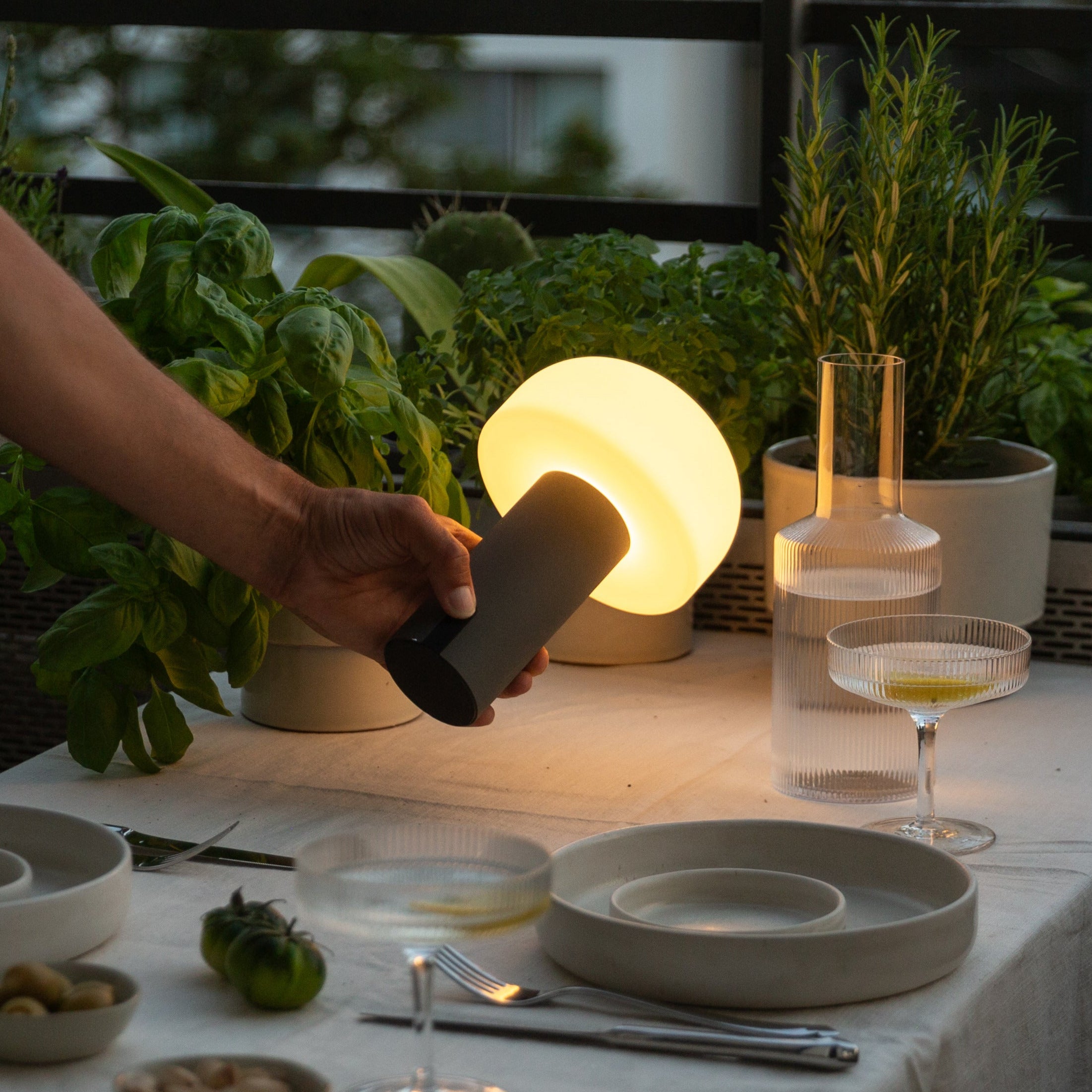 Noa LED-Akku-Tischleuchte in Grau – kabelloses Stimmungslicht für den gedeckten Terrassentisch mit Kräutern und Drinks bei Abenddämmerung