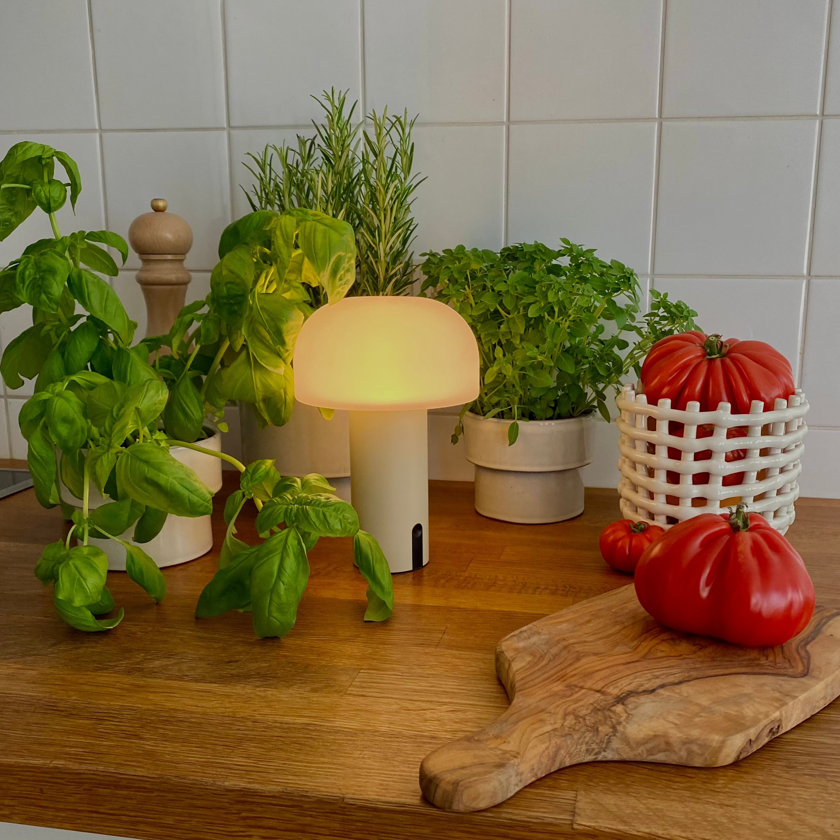 Moderne Design-Tischlampe Noa von LUUK Studio in natürlicher Küchenumgebung mit Basilikum, Keramik und Strauchtomaten