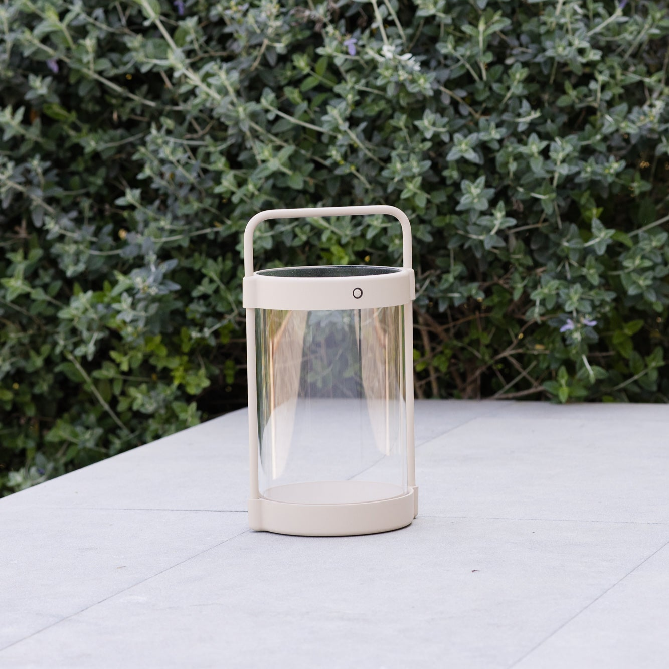 Weiße tragbare LED-Outdoorlampe von LUUK Studio mit Griff auf Betonfläche im Tageslicht