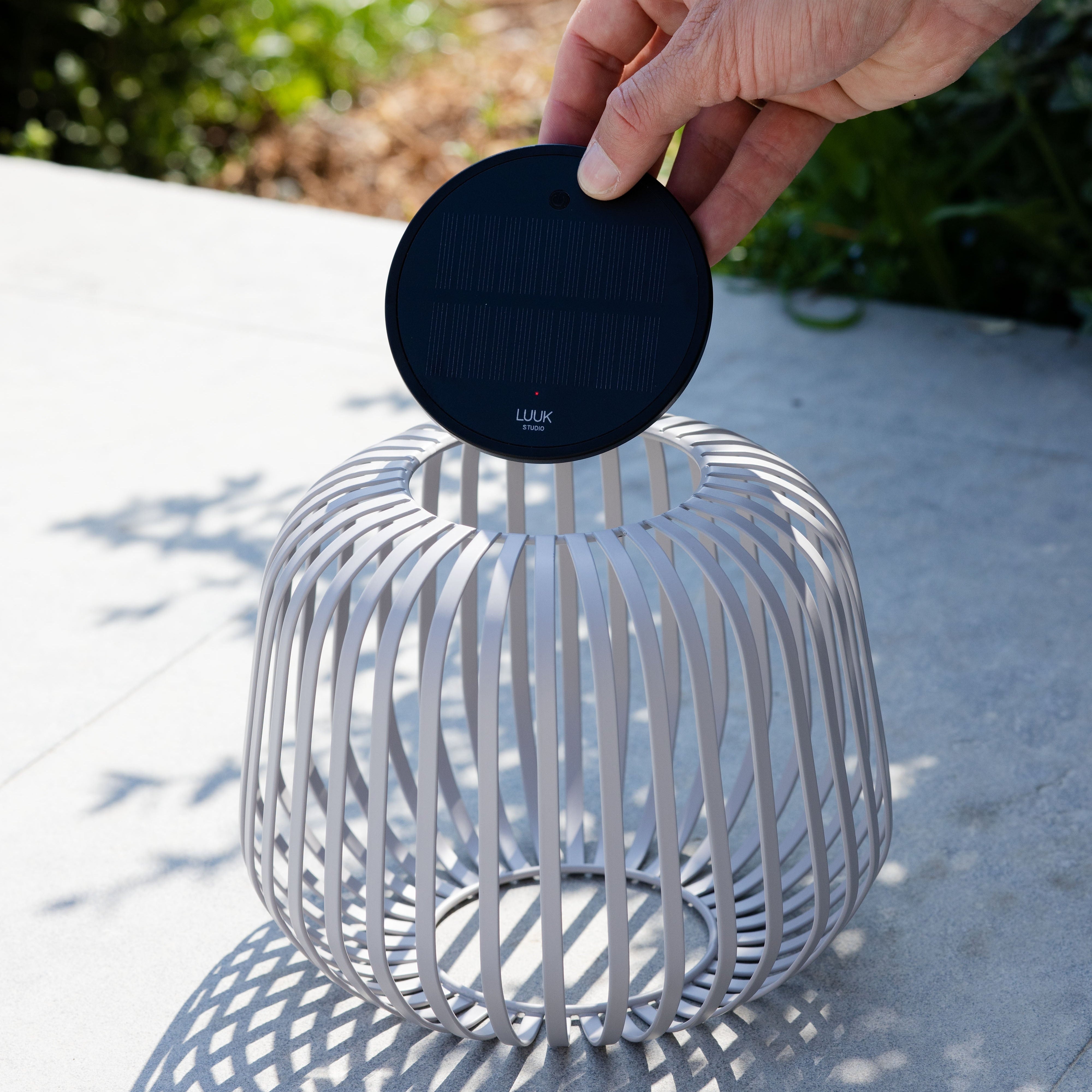 Solis Solarlaterne von LUUK Studio in weiss s auf einer Terrasse – entnehmbares Solarmodul wird gezeigt, ideal für stimmungsvolle Beleuchtung im Garten oder Outdoor-Bereich.