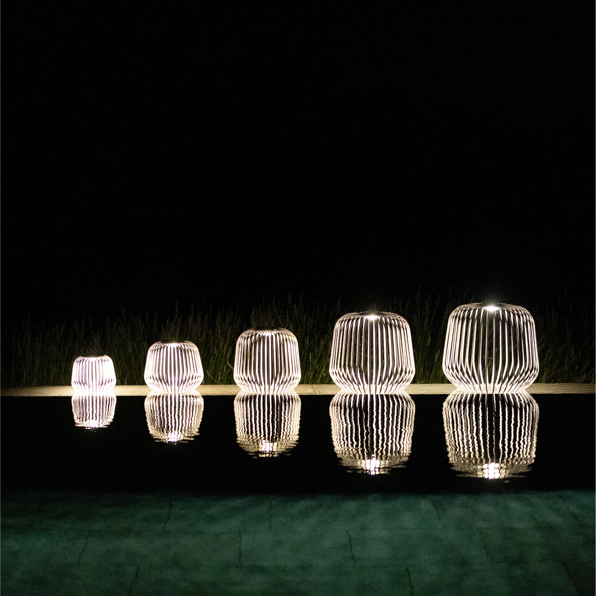 5er Set SOLIS von LUUK Studio in den Größen S, M, L, XL, XXL in Grau bei Nacht am Pool mit Spiegelung im Wasser