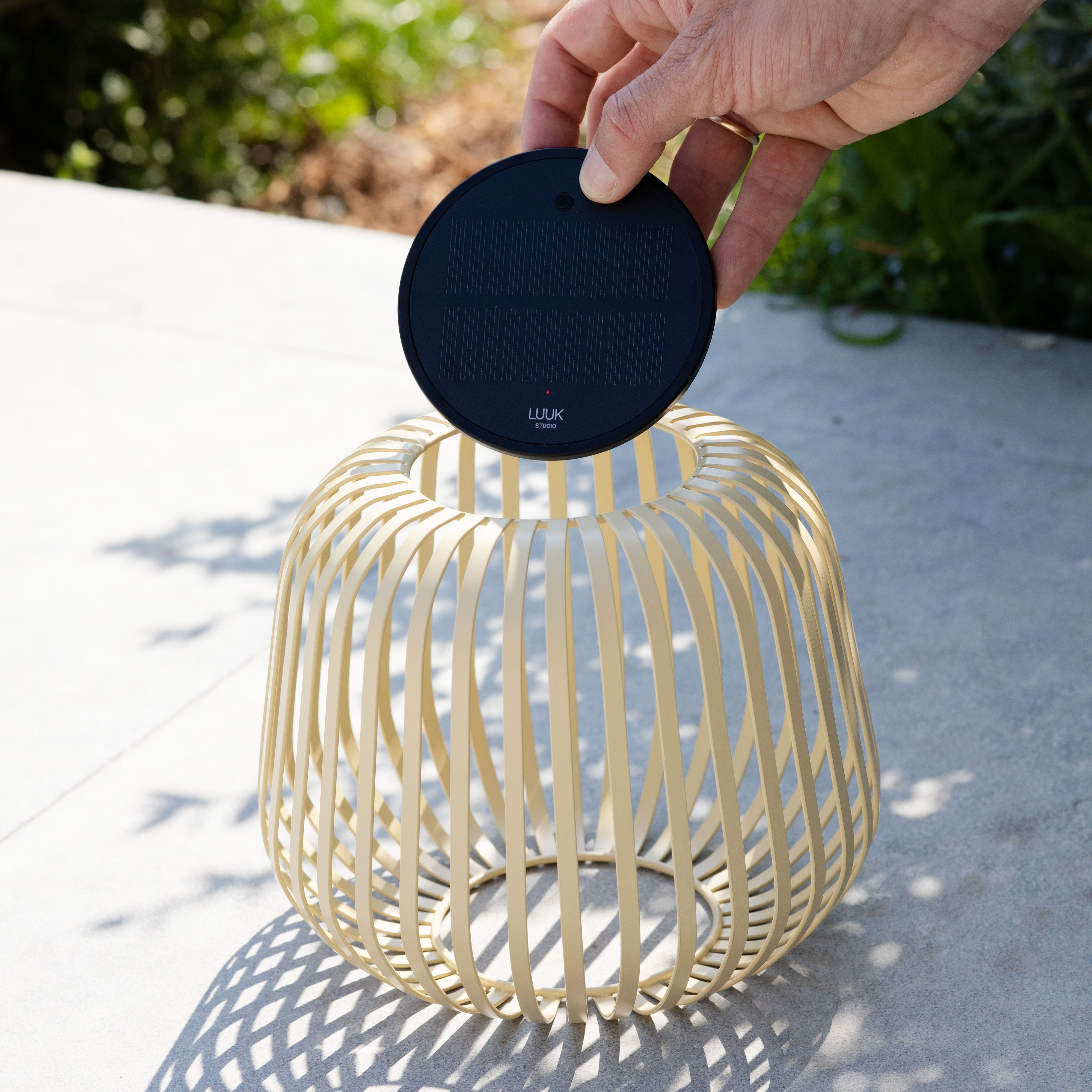 Solis Solarlaterne von LUUK Studio in sand s auf einer Terrasse – entnehmbares Solarmodul wird gezeigt, ideal für stimmungsvolle Beleuchtung im Garten oder Outdoor-Bereich.