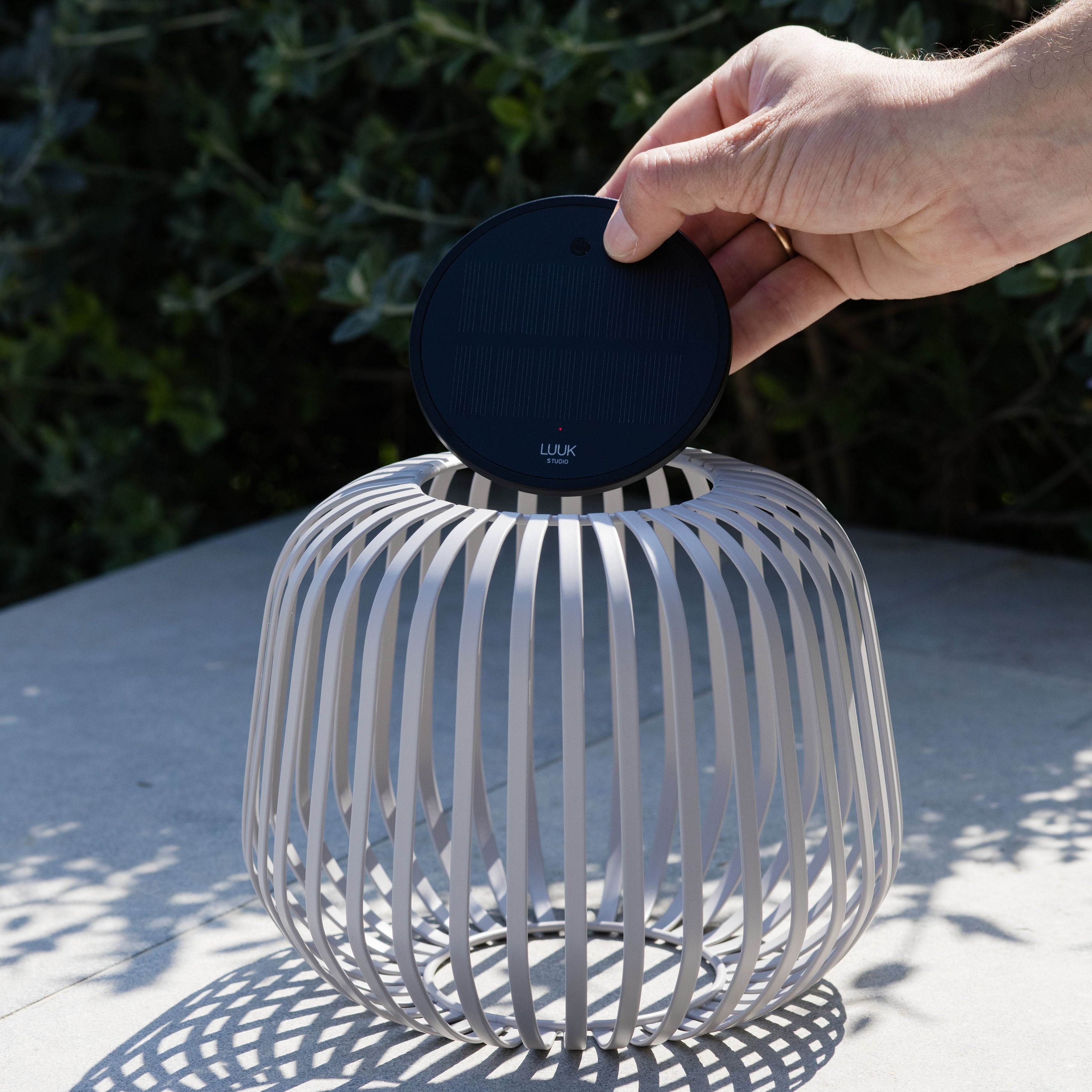 Solis Solarlaterne von LUUK Studio in grau s auf einer Terrasse – entnehmbares Solarmodul wird gezeigt, ideal für stimmungsvolle Beleuchtung im Garten oder Outdoor-Bereich.