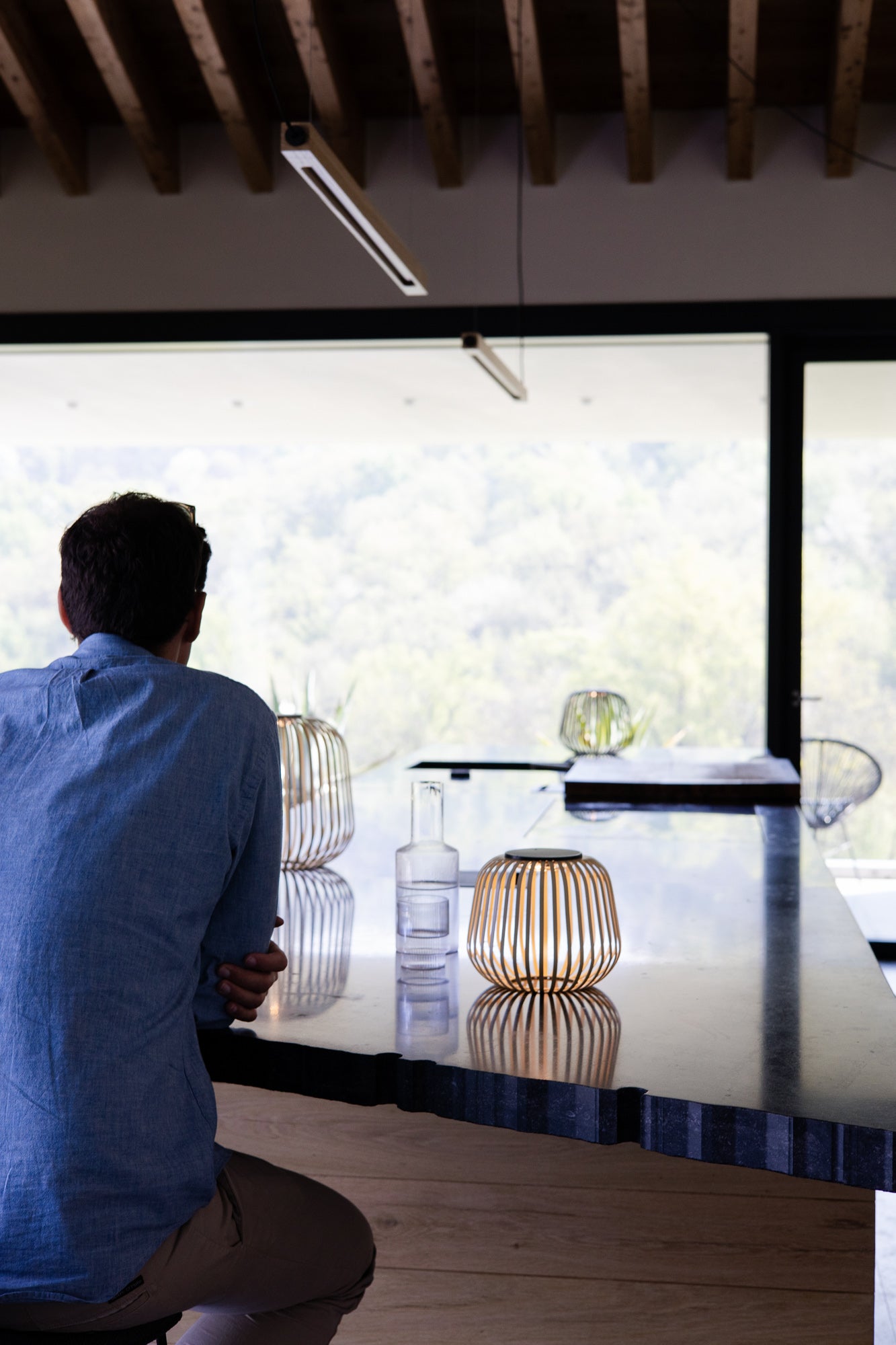 Design-Solarlaterne Solis auf einer Kücheninsel aus Naturstein, leuchtend bei Tageslicht – stilvolle Lichtquelle mit dekorativer Reflexion, ideal für moderne Wohnräume mit Ausblick ins Grüne.