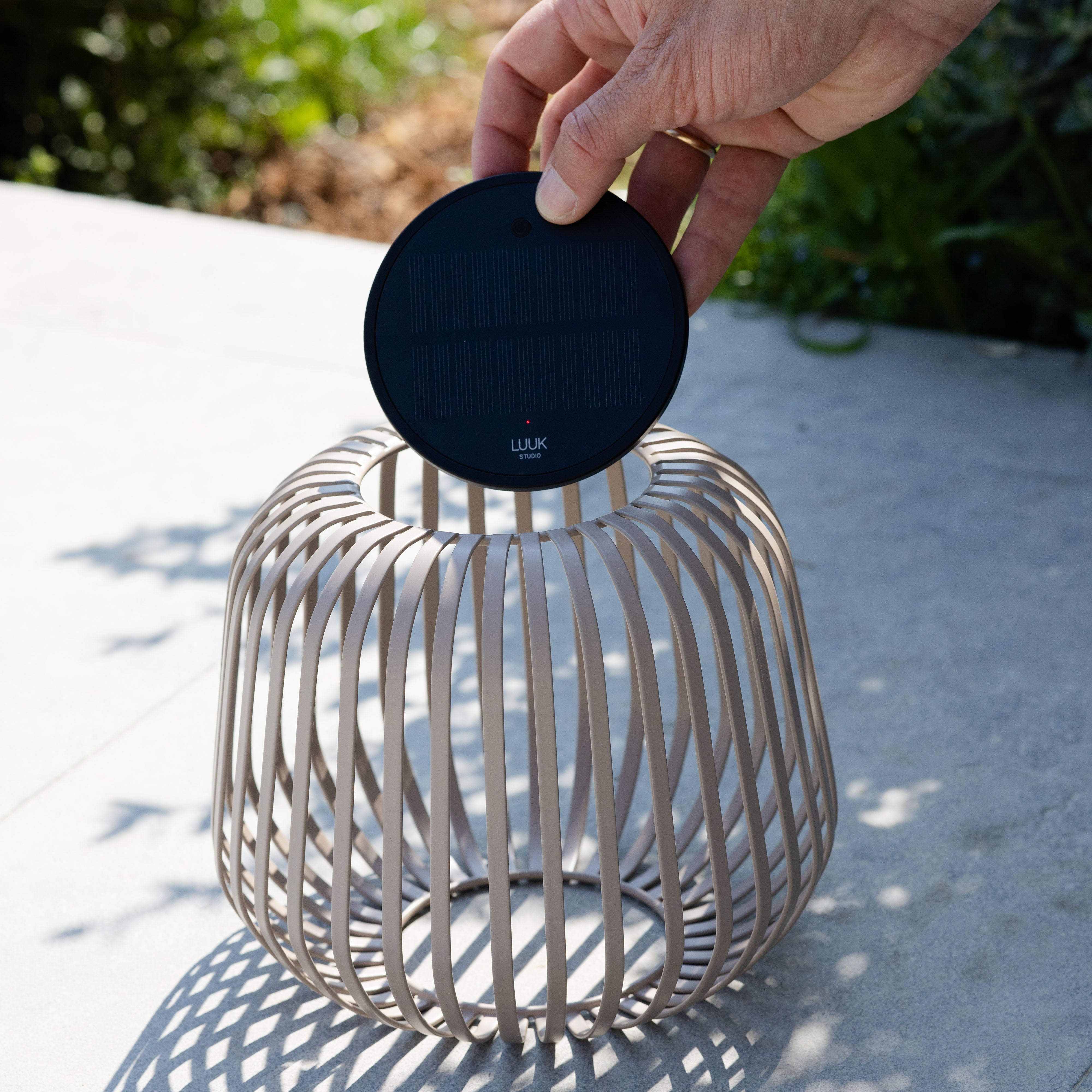 Solis Solarlaterne von LUUK Studio in Nomadbraun s auf einer Terrasse – entnehmbares Solarmodul wird gezeigt, ideal für stimmungsvolle Beleuchtung im Garten oder Outdoor-Bereich.