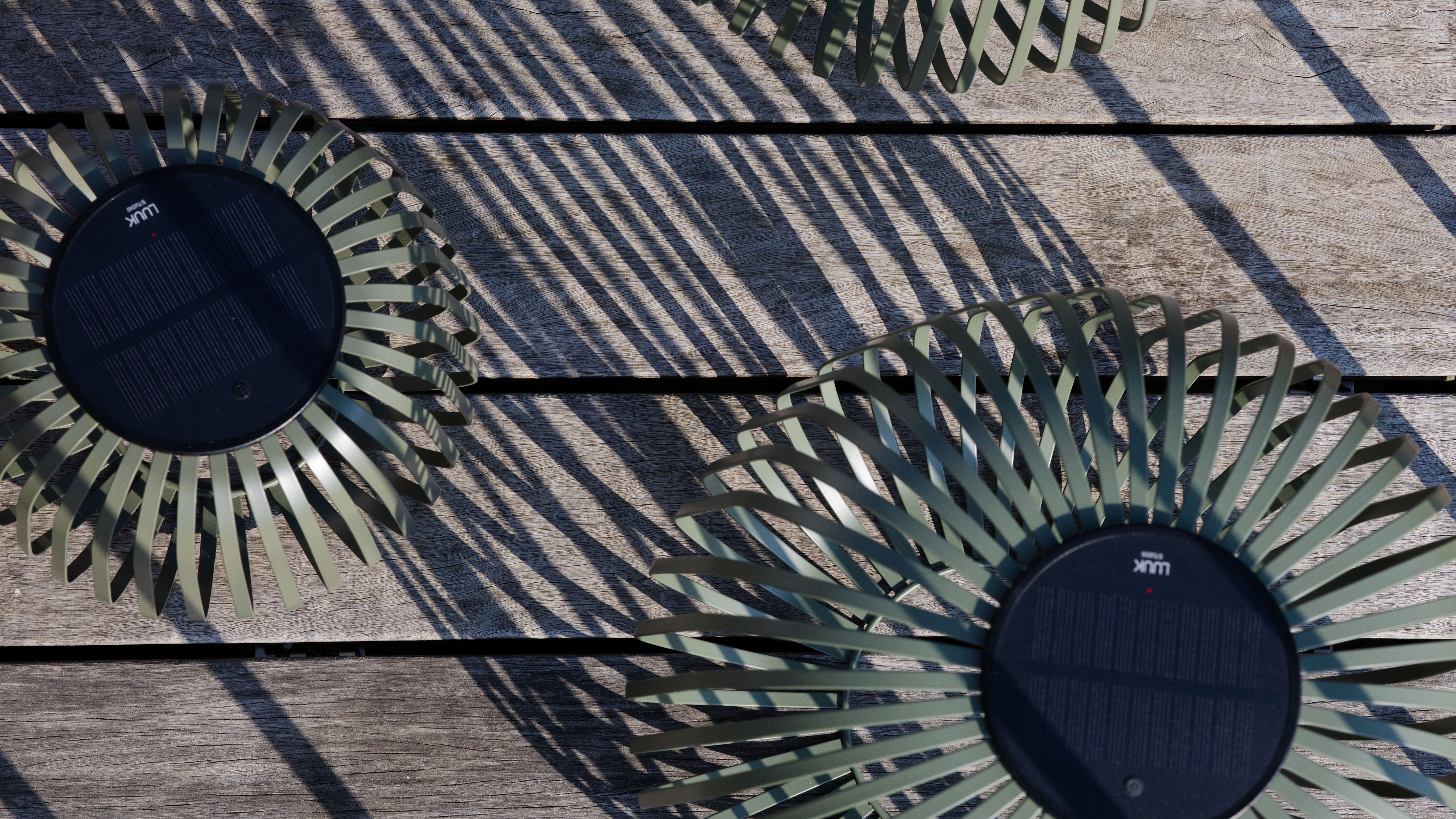 Zwei Solis Solarlaternen von oben fotografiert mit sichtbarem Solarpanel auf einer Holzterrasse – zeigen die nachhaltige Energiequelle für stimmungsvolle Outdoor-Beleuchtung