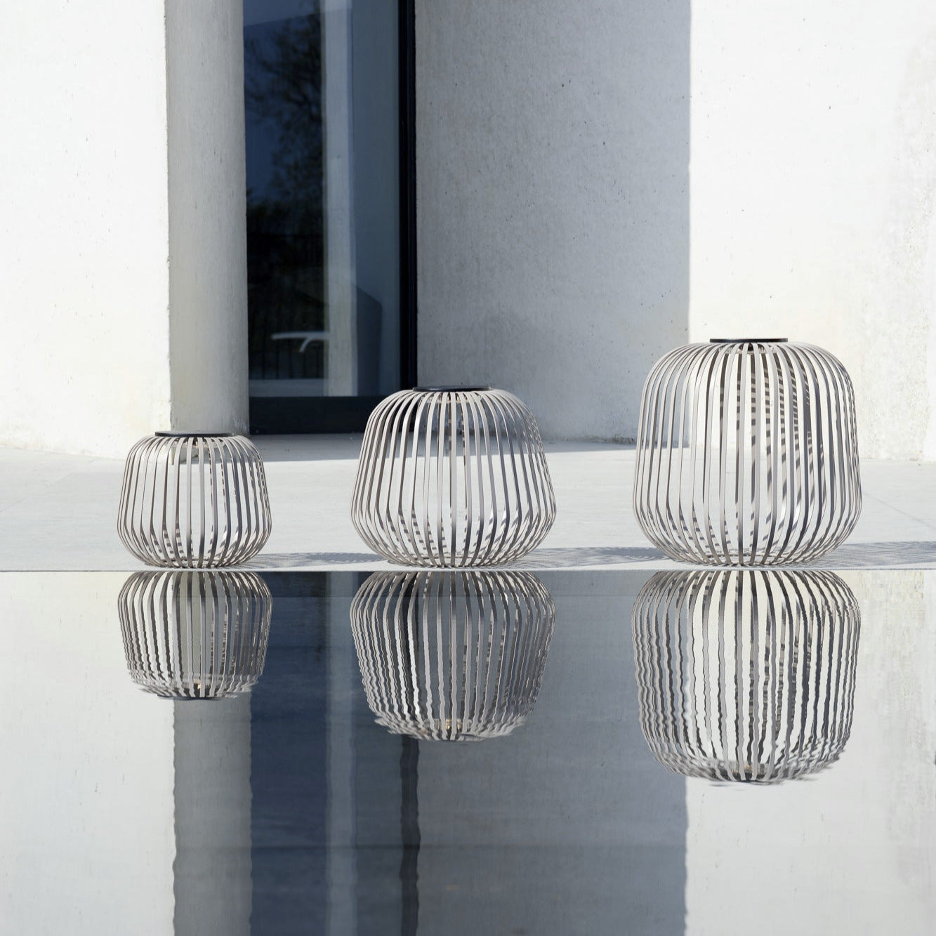 Drei SOLIS Solarleuchten in Nomand in verschiedenen Größen, modernes Cage-Design, wetterfestes Outdoor-Lichtobjekt mit reflektierender Wirkung – ideal für Terrasse oder Garten