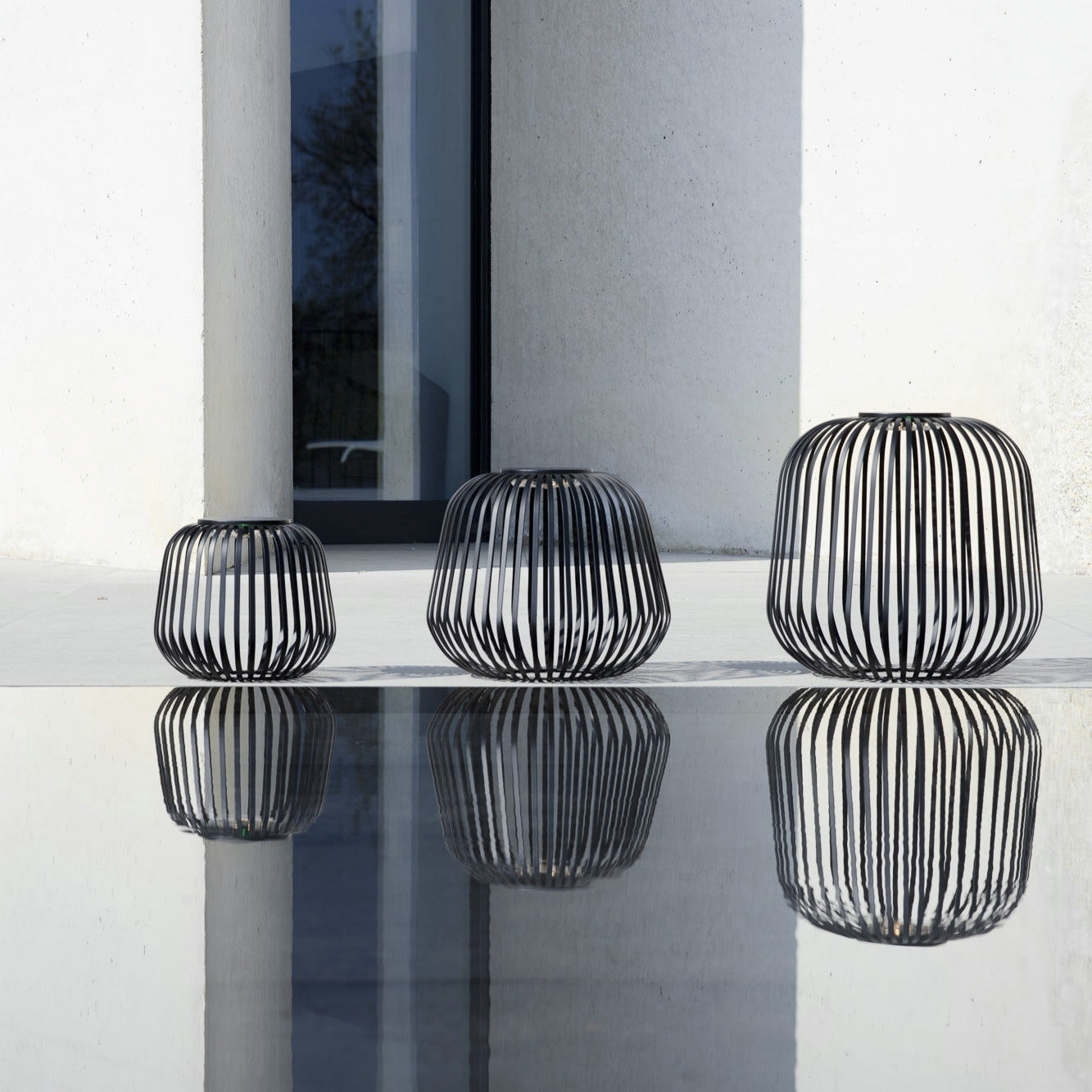 Drei SOLIS Solarleuchten in Schwarz in verschiedenen Größen, modernes Cage-Design, wetterfestes Outdoor-Lichtobjekt mit reflektierender Wirkung – ideal für Terrasse oder Garten