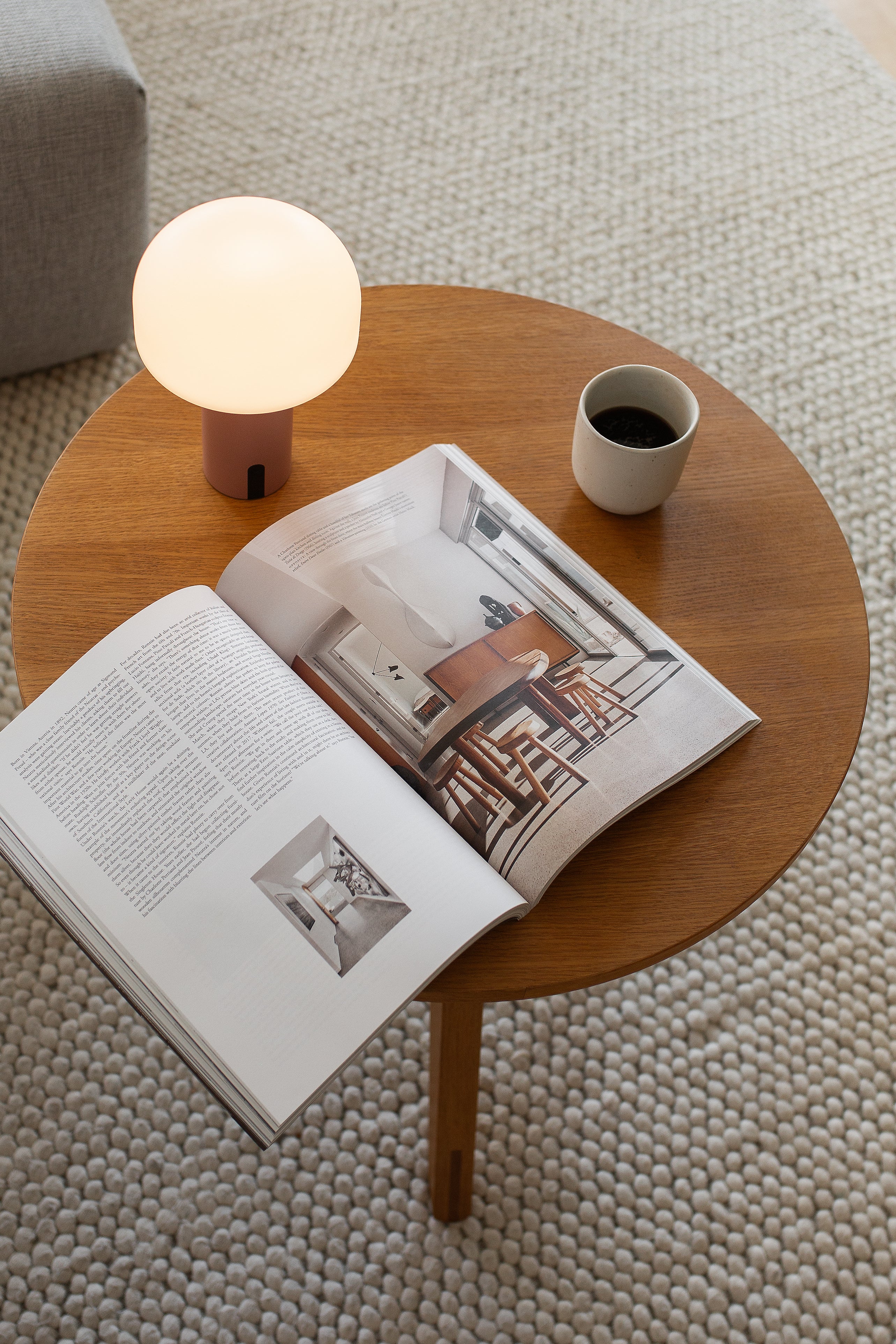 Rote LED-Designlampe Noa auf Holz-Couchtisch mit offenem Magazin – minimalistisches Wohnambiente mit LUUK Studio Leuchte
