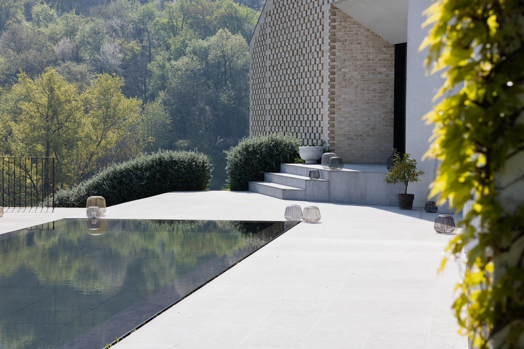 Naturpool mit Natursteinterrasse und Solis Solarlampen bei Tag