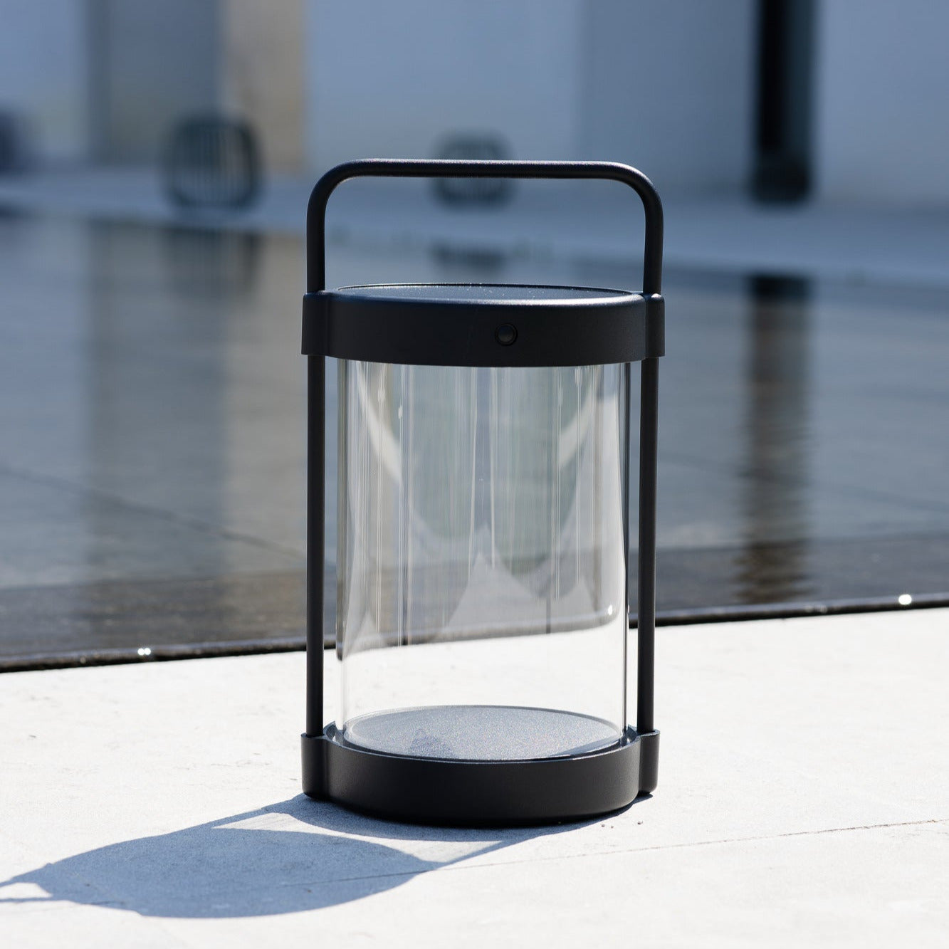 Caia LED Laterne in Schwarz mit Glaskubus vor Naturpool auf Steinterrasse