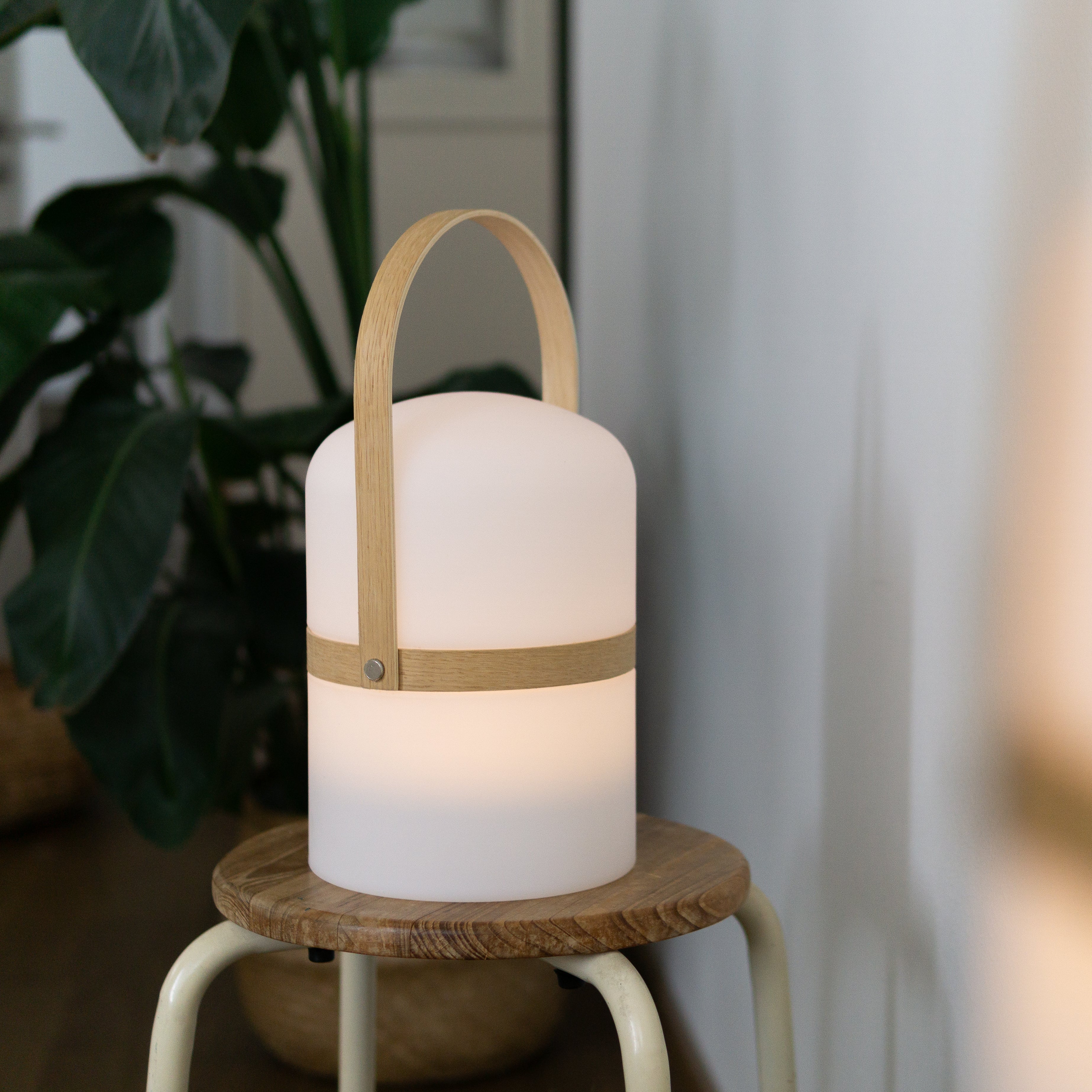 Kabellose Luma Laterne in weiß auf kleinem Holzstuhl als Stimmungslicht im Wohnzimmer 