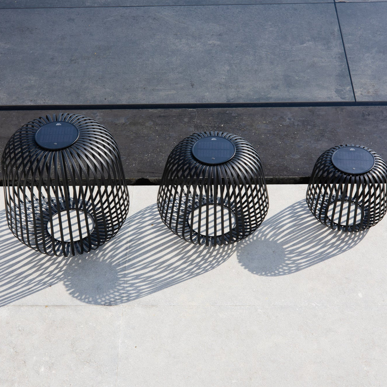 Drei schwarze Solis Laternen aus Metall mit herausnehmbaren Modul bei Tageslicht auf einer Terrasse – stimmungsvolles Outdoor-Licht und stilvolles Windlicht für Garten, Balkon oder Eingangsbereich