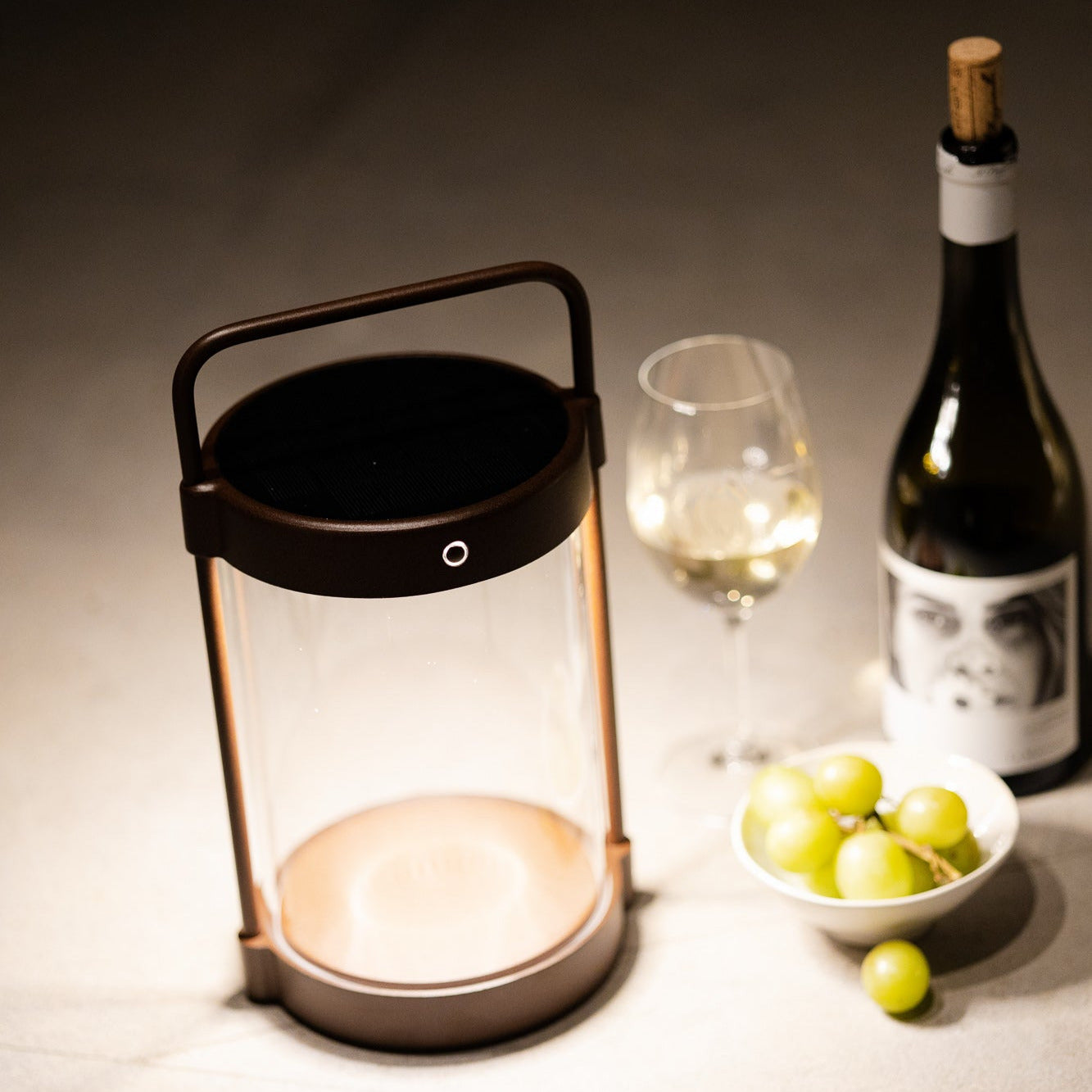 Braune Caia Solarlaterne mit Echtglas als stimmungsvolles Tischlicht beim Abendessen mit Wein und Trauben – kabellos, dimmbar und elegant für den Außenbereich