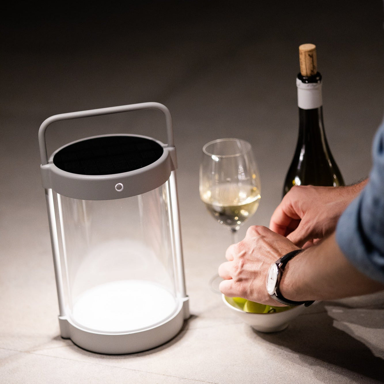 Dimmbare Caia LED-Solarlaterne in Grau mit Echtglas bei einem gedeckten Tisch – stimmungsvolle Beleuchtung am Abend mit Wein und Snacks im Freien