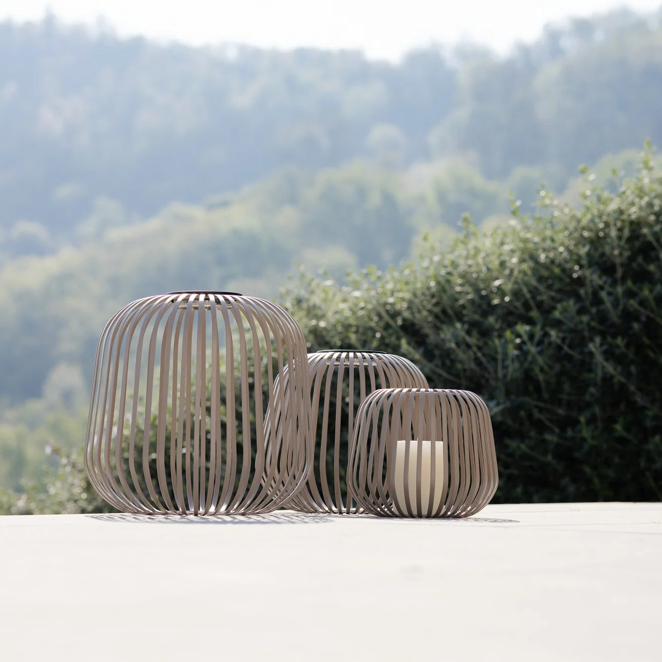 3er-Set Nomad Laternen mit Solarmodul und Kerzenhalter Option im Sonnenlicht auf Terrasse – mobile Designleuchten für stimmungsvolle Beleuchtung im Außenbereich, ideal für Garten, Balkon oder Lounge-Zonen
