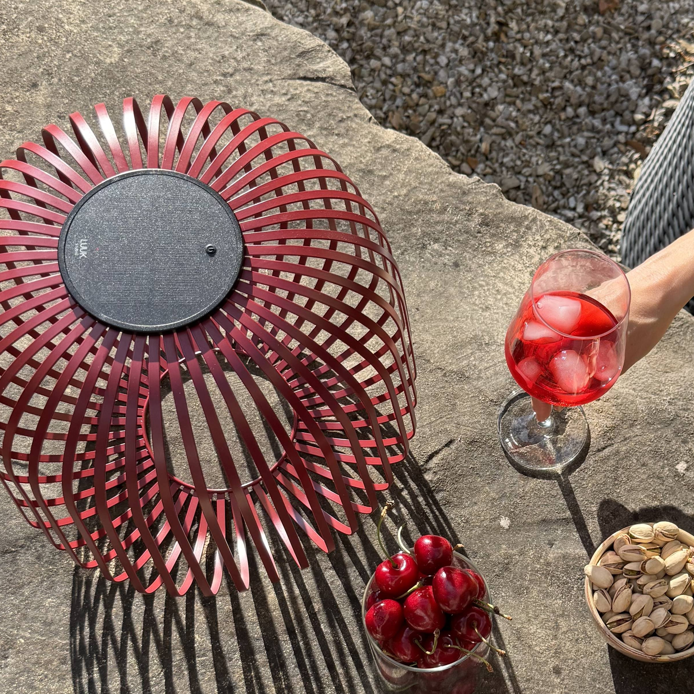 LUUK Studio Solarlampe in Größe L auf Steintisch mit Sommerdrinks und Snacks