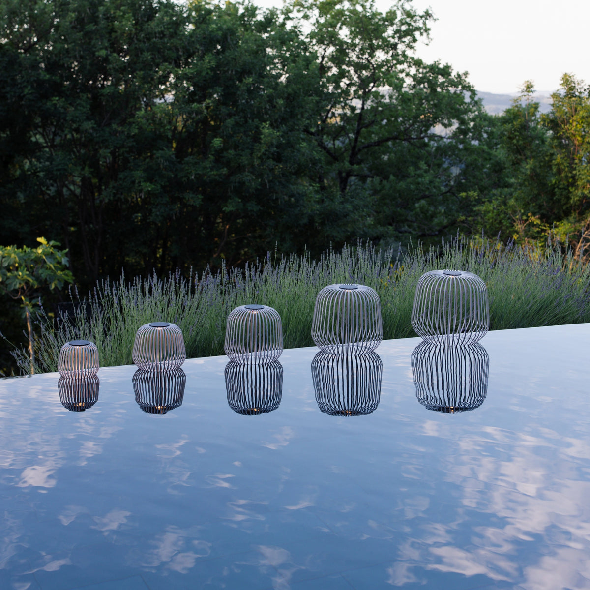 5er Set SOLIS von LUUK Studio in den Größen S, M, L, XL, XXL in Grau am Pool mit Spiegelung im Wasser