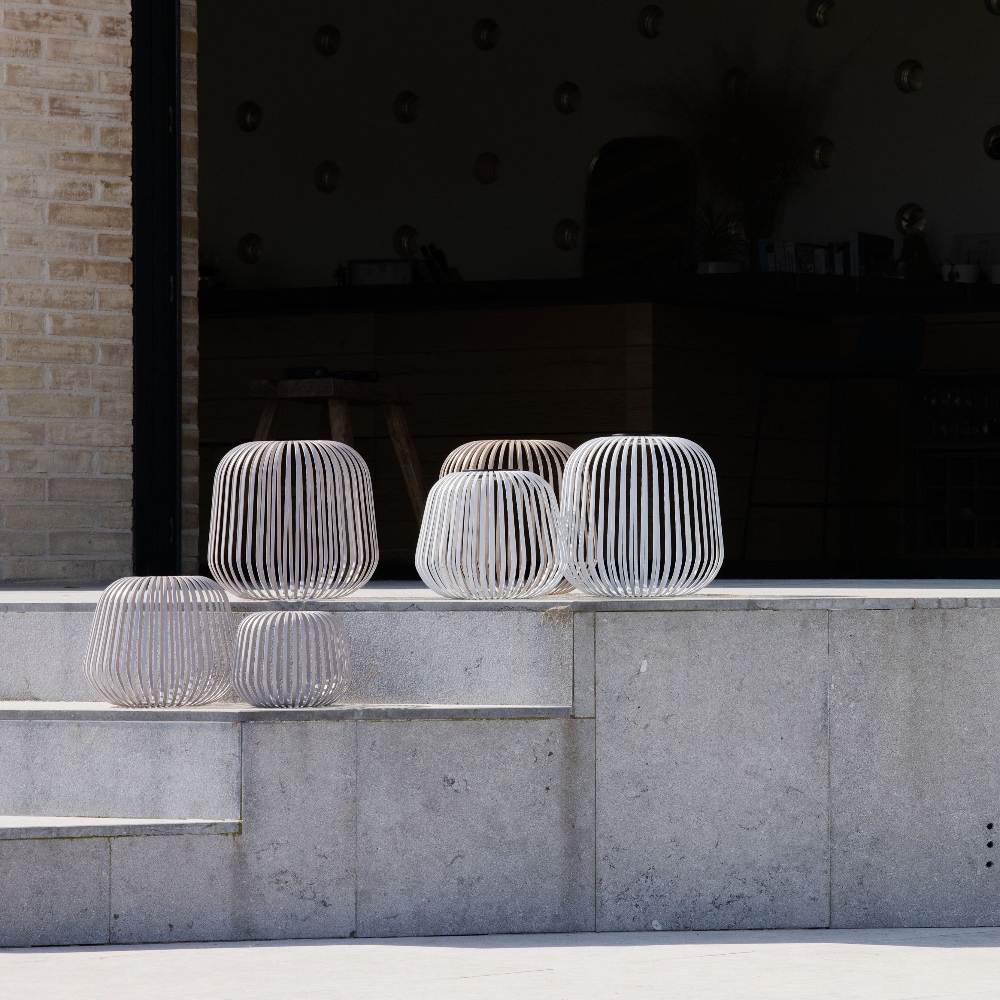Solis Solarlaternen in verschiedenen Farben als stilvolle Windlichter auf einer modernen Terrasse – ideal als Kerzenhalter für stimmungsvolle Outdoor-Beleuchtung in Garten oder auf dem Balkon