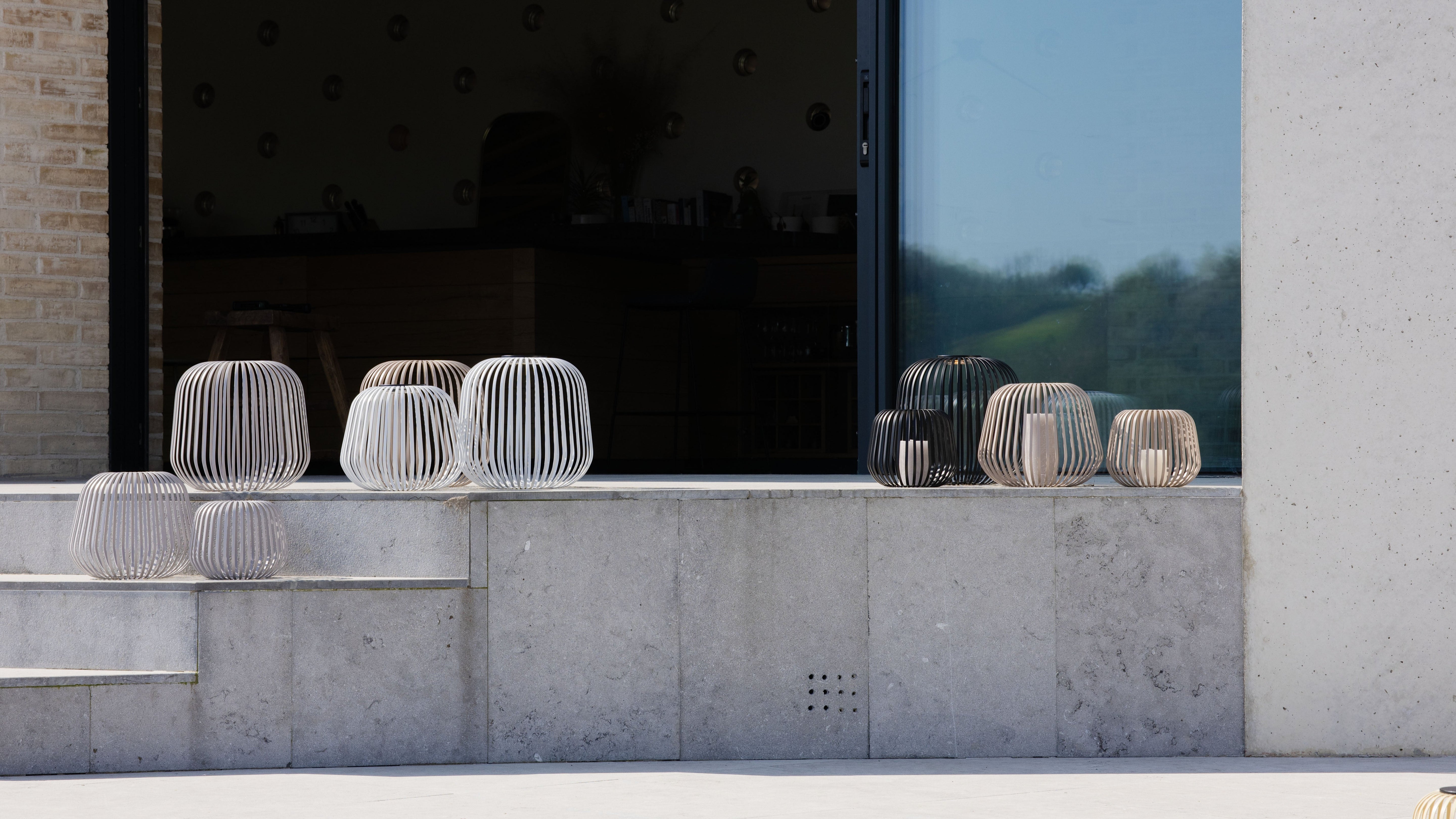 Solis Solarlaternen in verschiedenen Farben als stilvolle Windlichter auf einer modernen Terrasse – ideal als Kerzenhalter für stimmungsvolle Outdoor-Beleuchtung in Garten oder auf dem Balkon