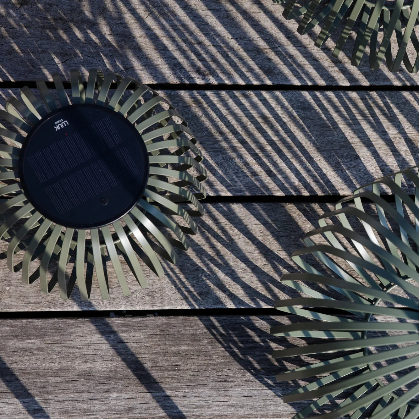 Solis Solarlaternen von oben fotografiert mit sichtbarem Solarpanel auf einer Holzterrasse – zeigen die nachhaltige Energiequelle für stimmungsvolle Outdoor-Beleuchtung