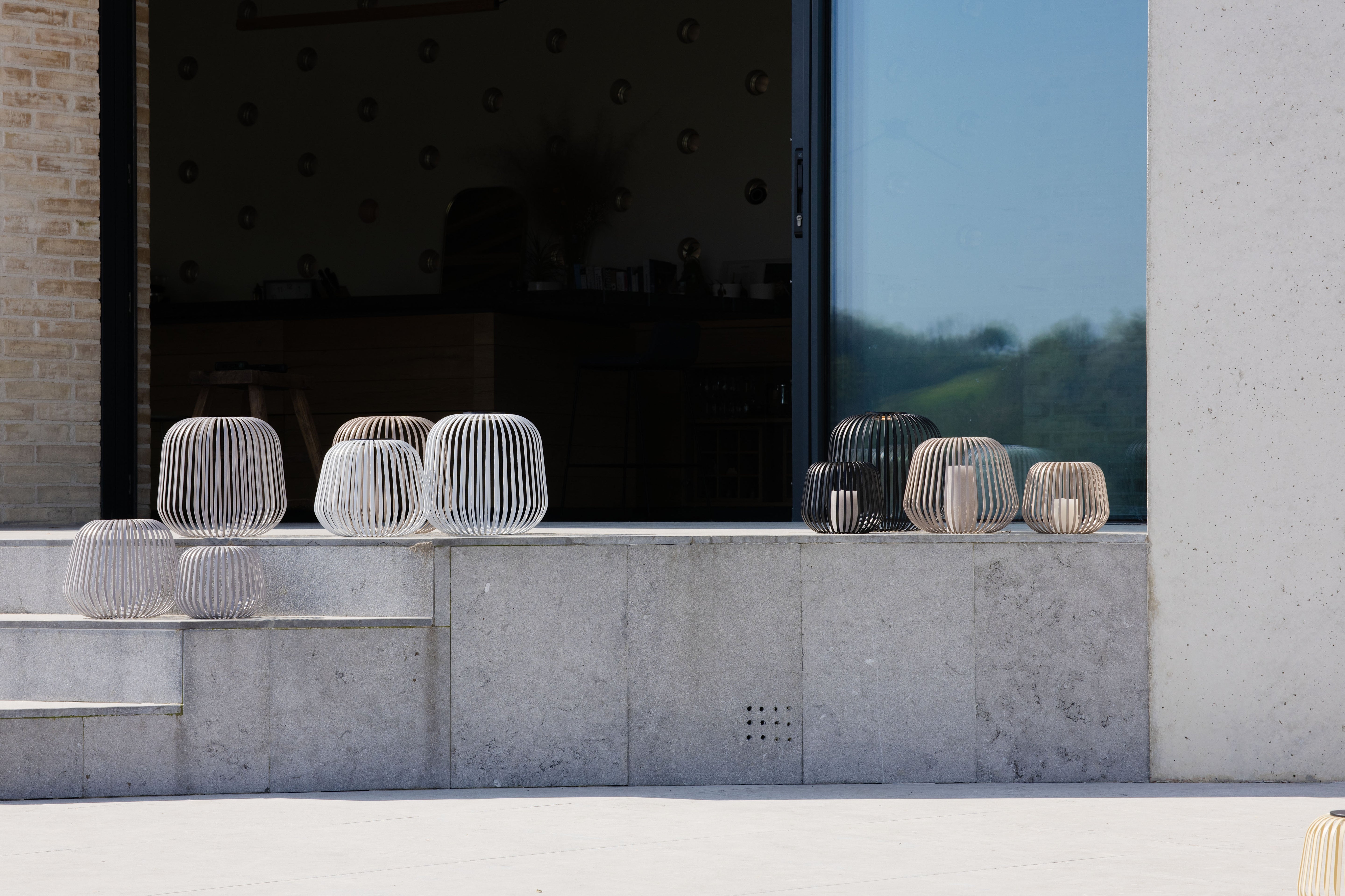 Mehrere LUUK Studio Solis Solarlaternen in verschiedenen Farben und Größen auf einer modernen Fensterbank – ideal für stimmungsvolle Beleuchtung auf der Terrasse, am Haus oder im Eingangsbereich.